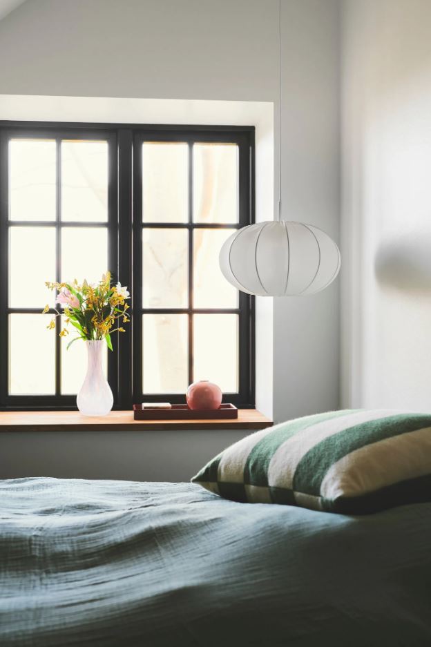Bedroom with window, pendant light, and flowers on a table.