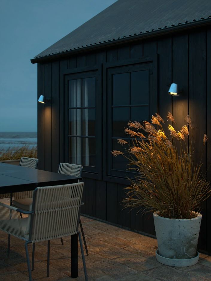 Dark wooden hut with outdoor seating and outdoor lighting at night.