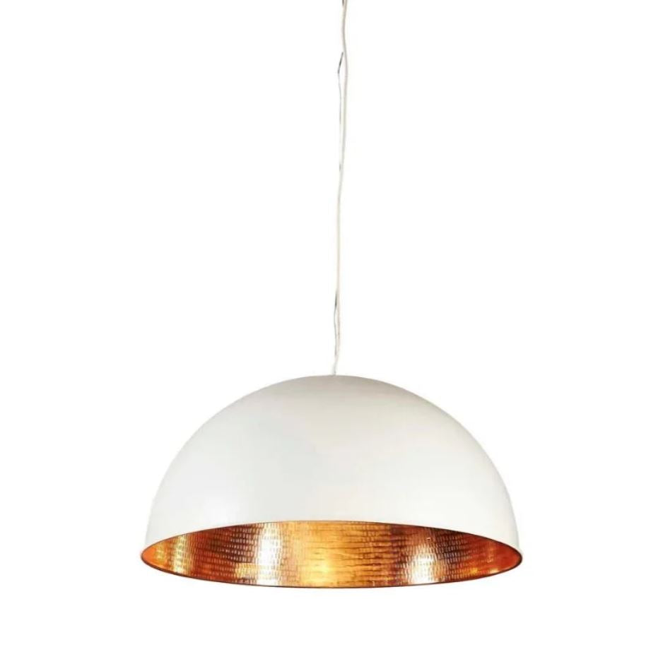 A modern industrial pendant light with a brass metal dome, featuring a white exterior and a polished brass interior, suspended above a living room setting.