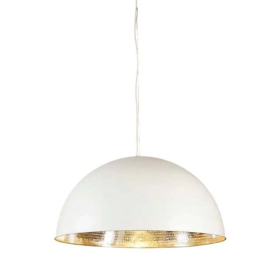 A modern industrial pendant light with a brass metal dome, featuring a white exterior and a polished brass interior, suspended above a living room setting.