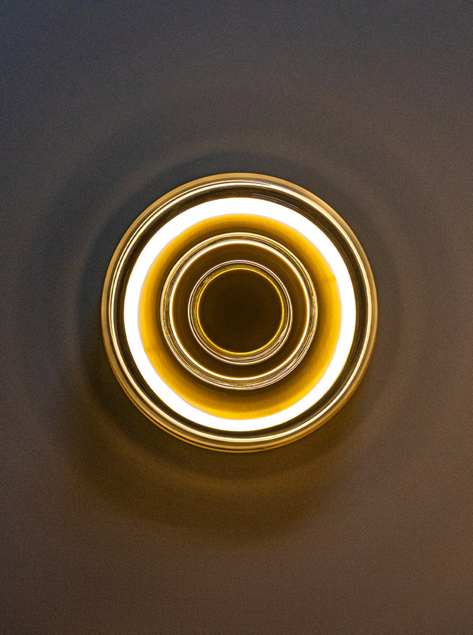 Circular wall light fixture with concentric rings on a dark background