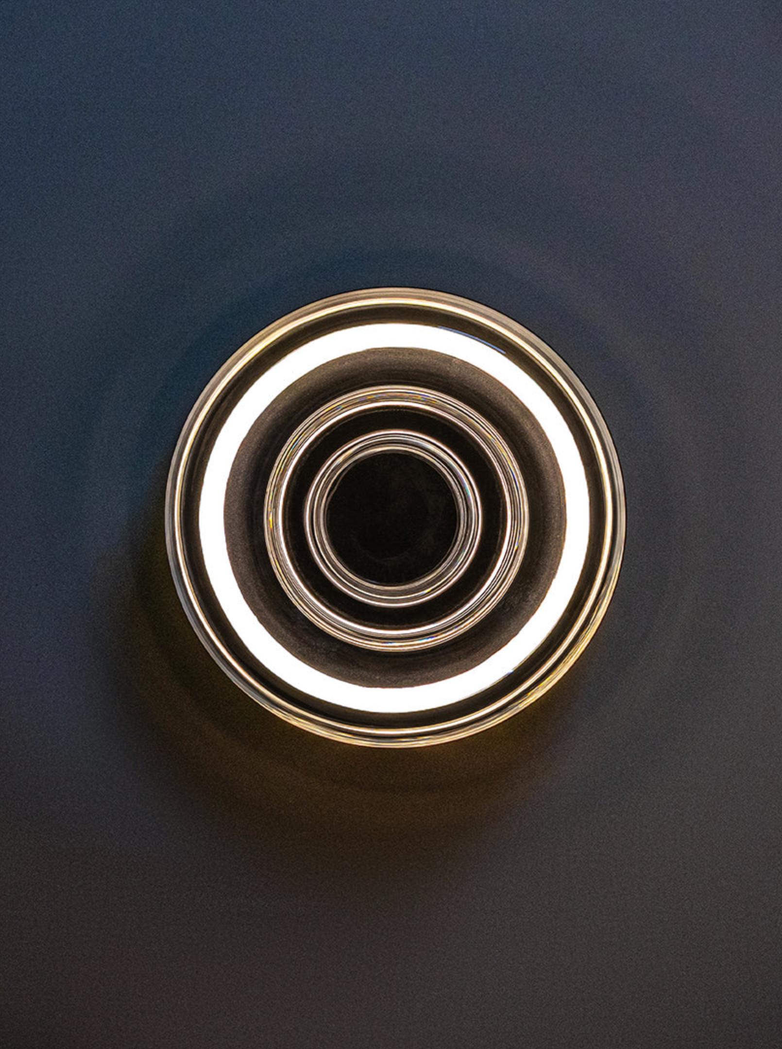 Glass wall light with concentric rings on a dark background