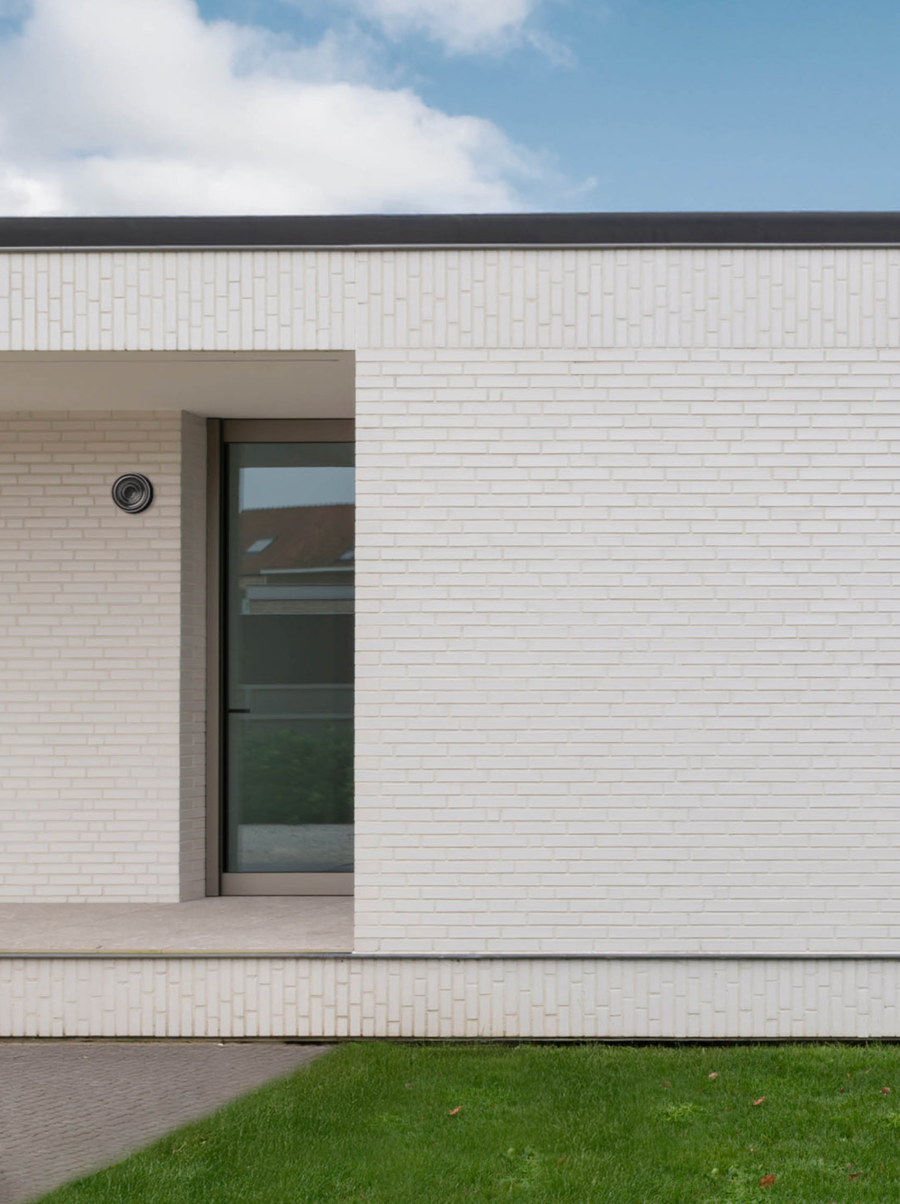 Modern house exterior with white brick facade and glass door