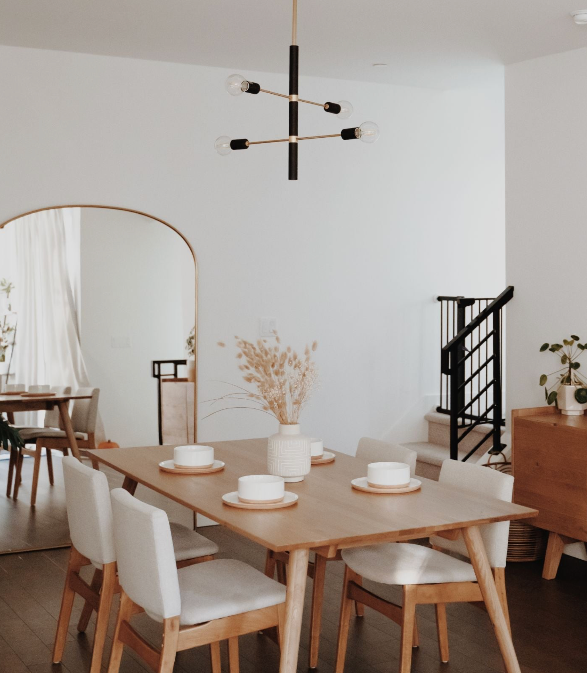 Dining room with wooden table, white chairs, and a modern pendant light fixture.