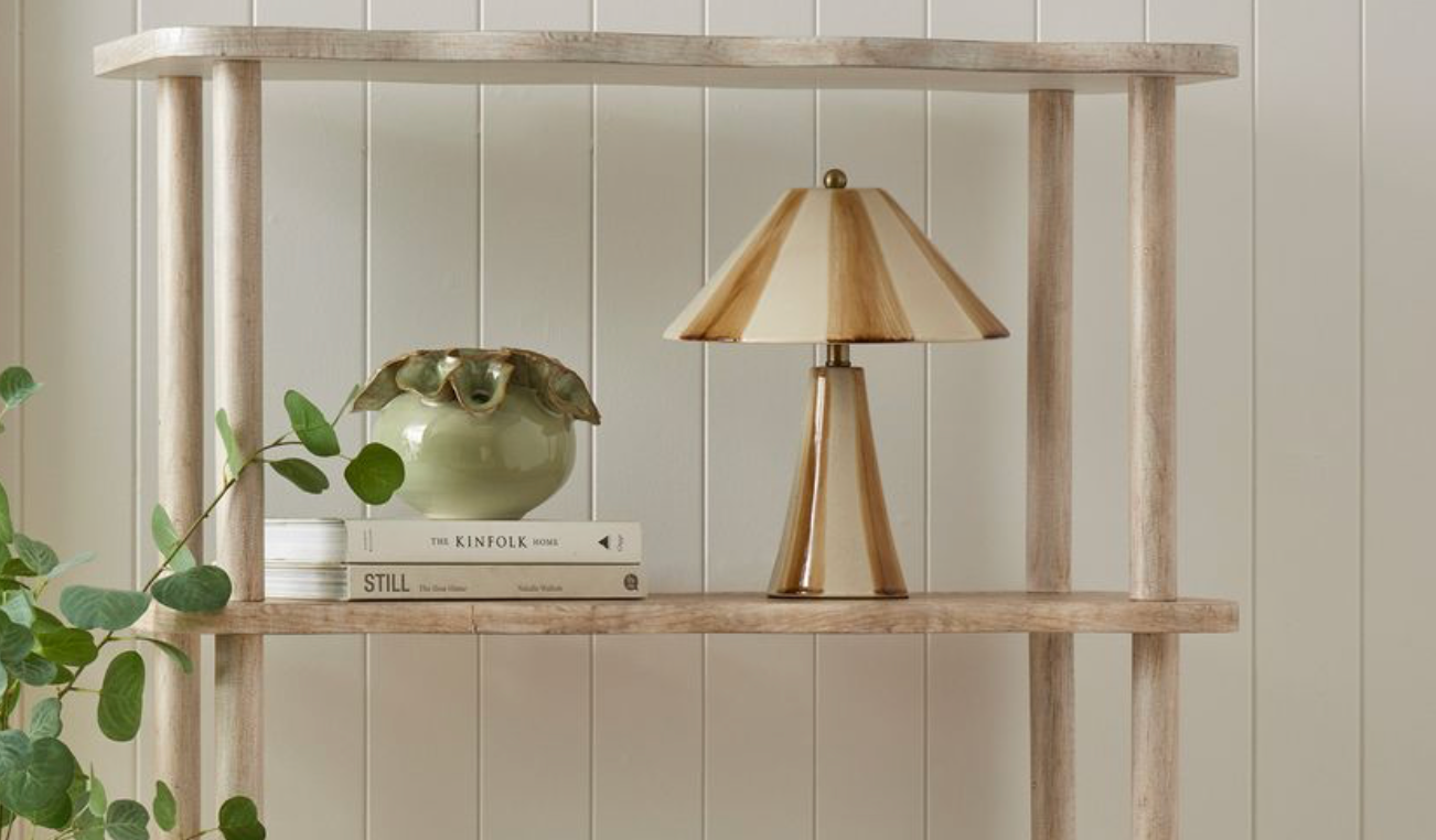 Wooden shelf with a lamp and books against a light wooden paneled wall