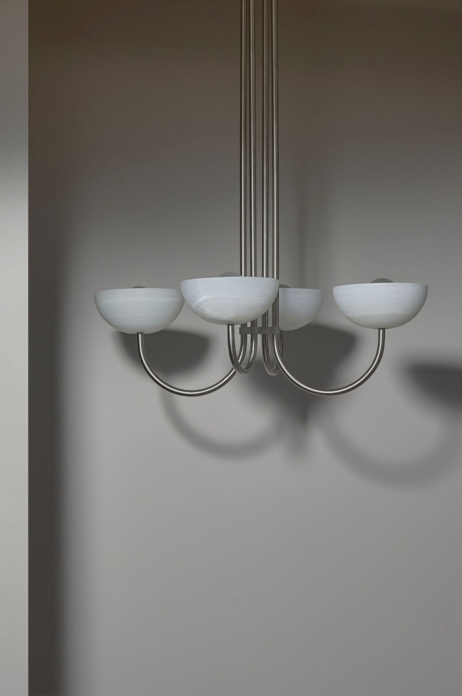 Chandelier with five white stone shades on a plain wall