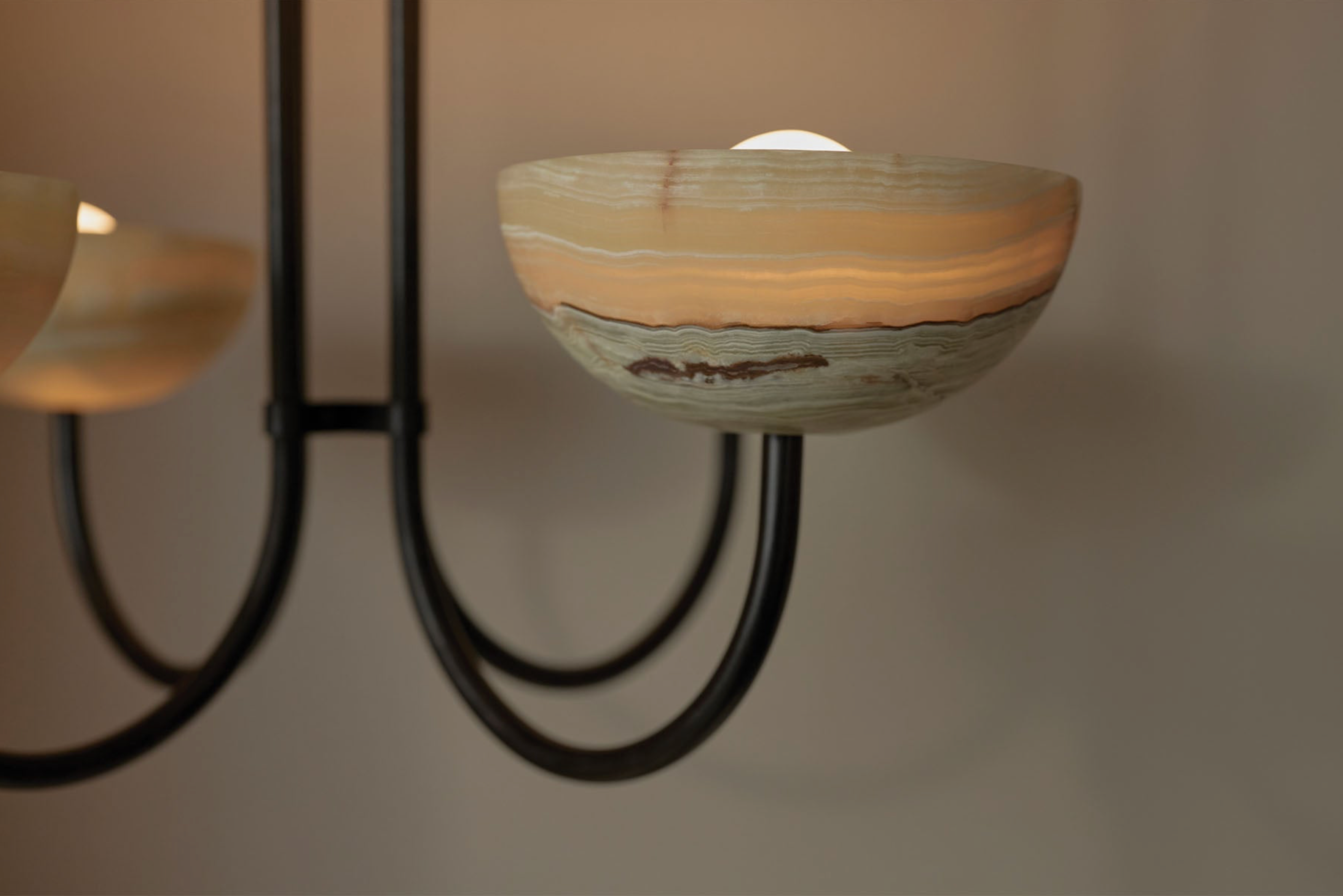 Stone bowl shaped light shade with a textured surface on a black metal stand against a neutral background