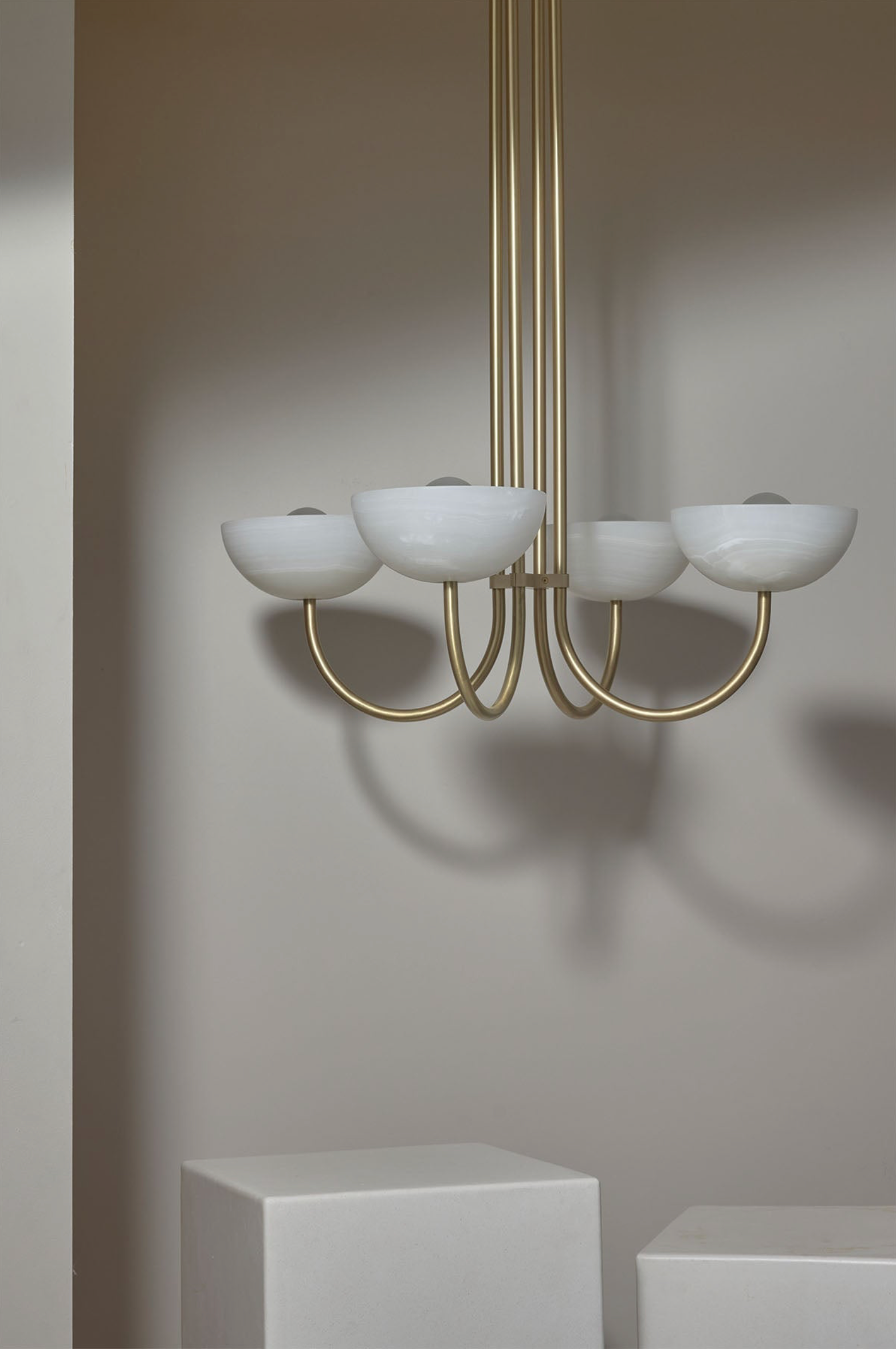 Modern chandelier with white stone shades and gold metal frame on a neutral background
