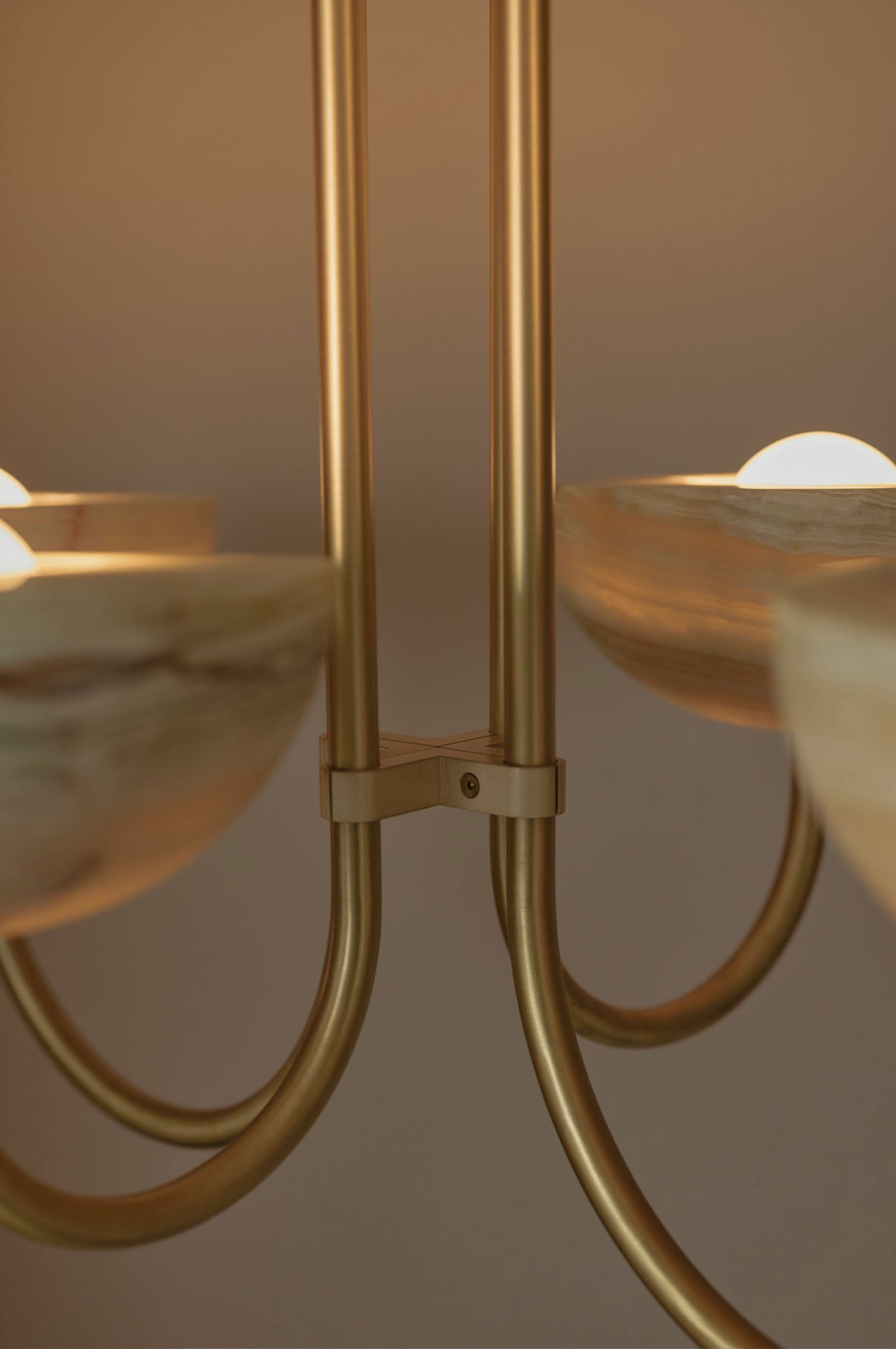 Close-up of a gold chandelier with glass shades against a neutral background