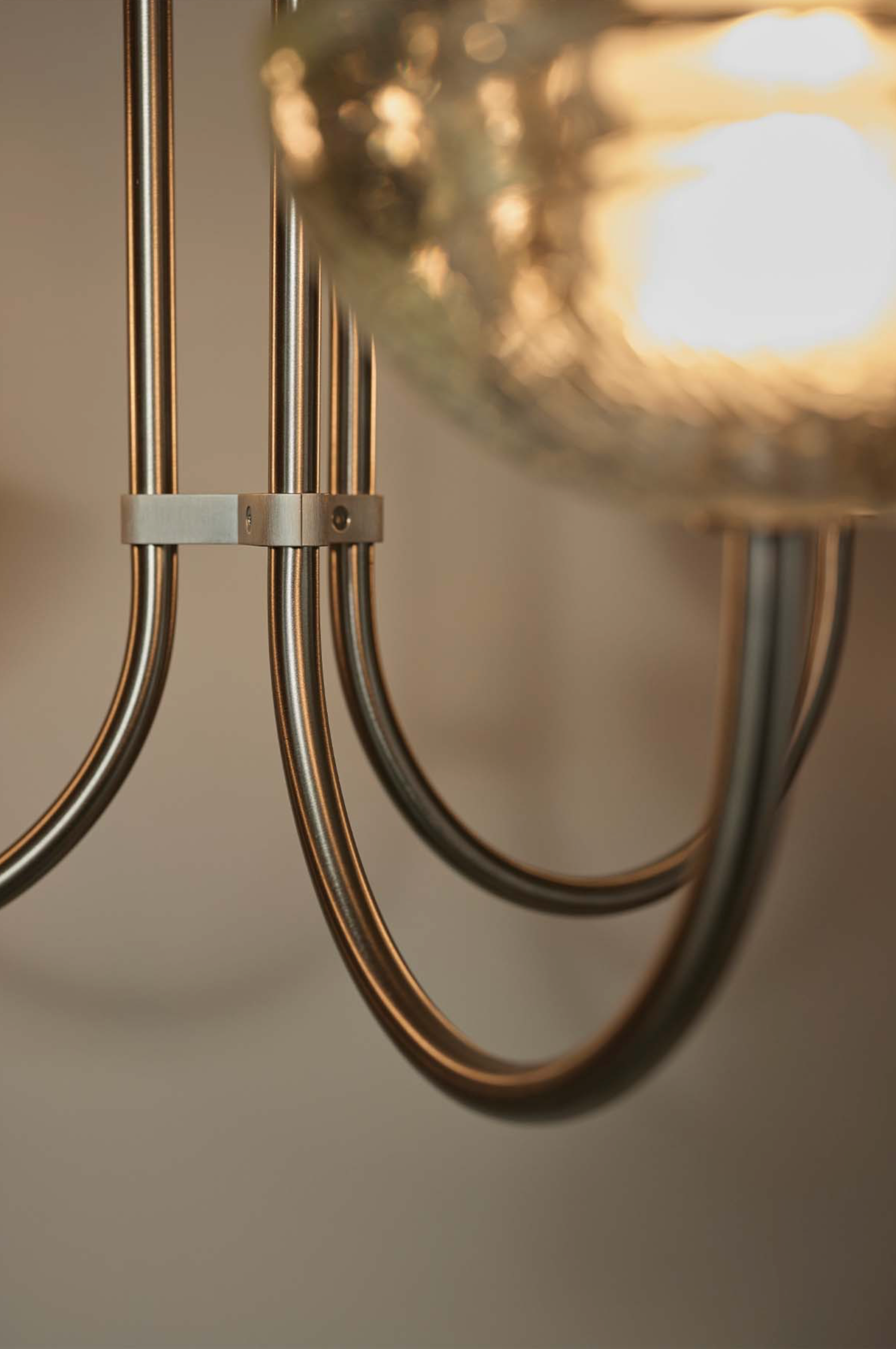 Close-up of a modern chandelier with metallic finish and glass shade.