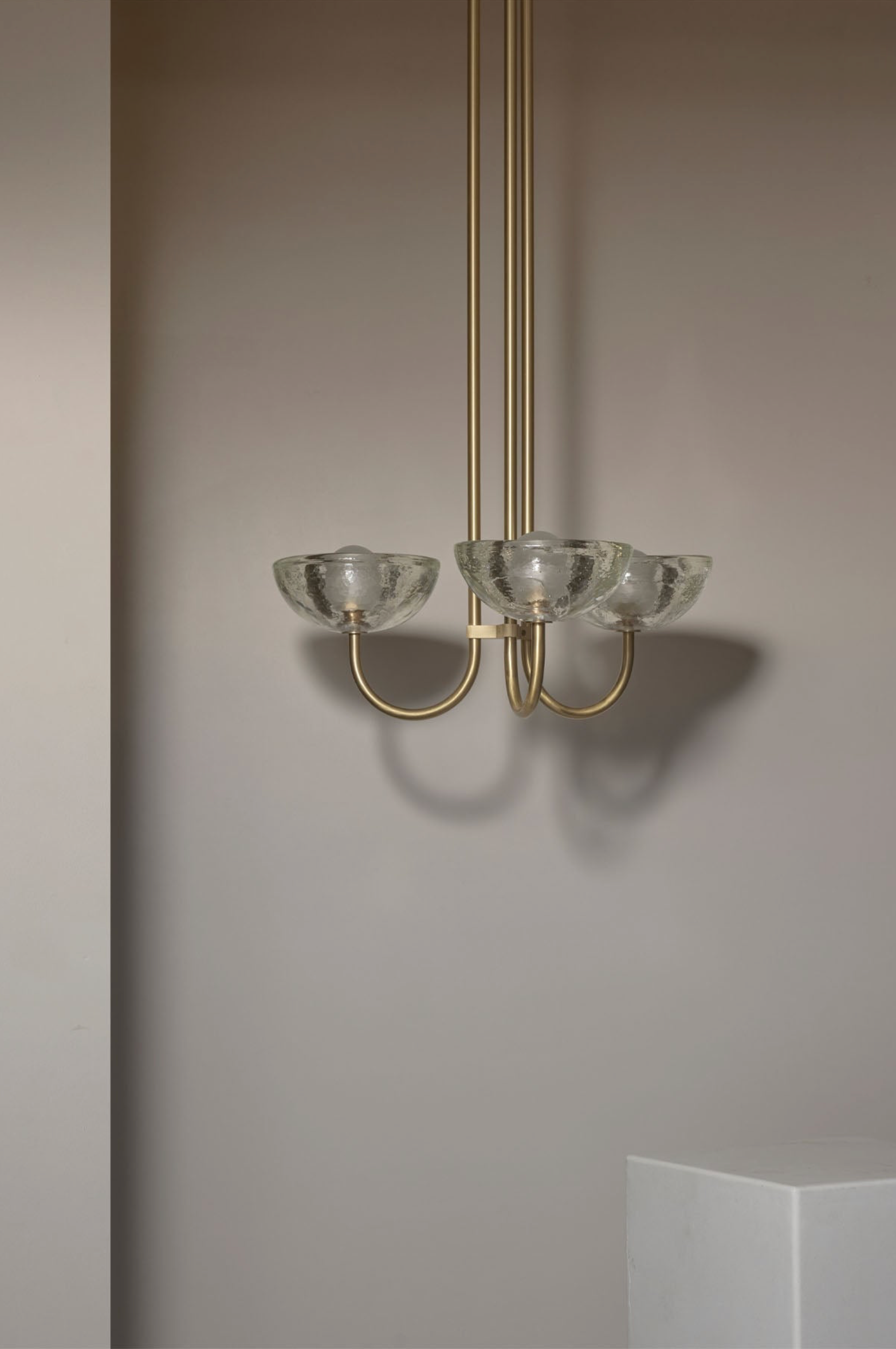 Chandelier with glass shades and gold fixtures against a neutral wall.