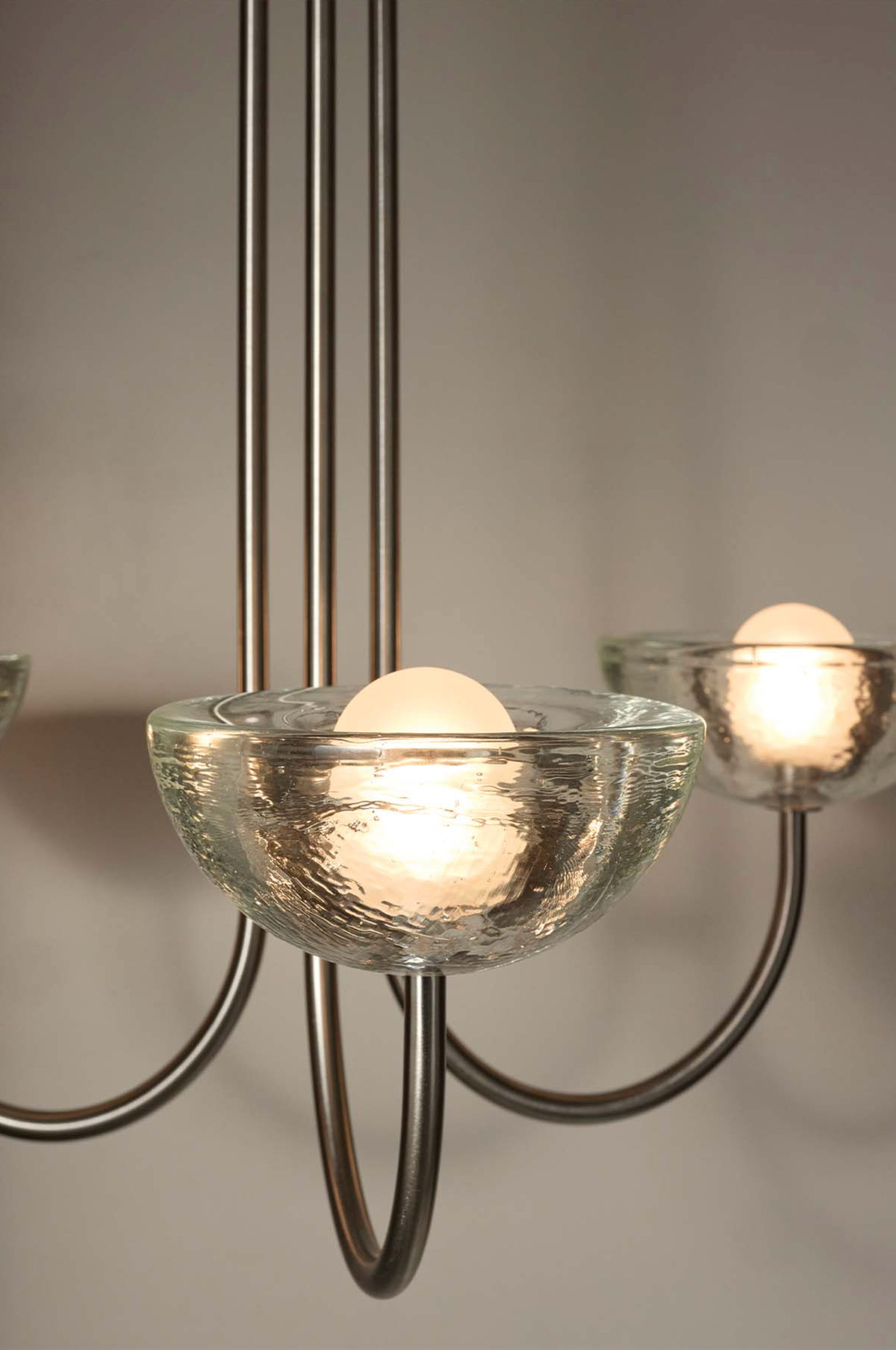 Close-up of a chandelier with glass shades and metal arms on a neutral background