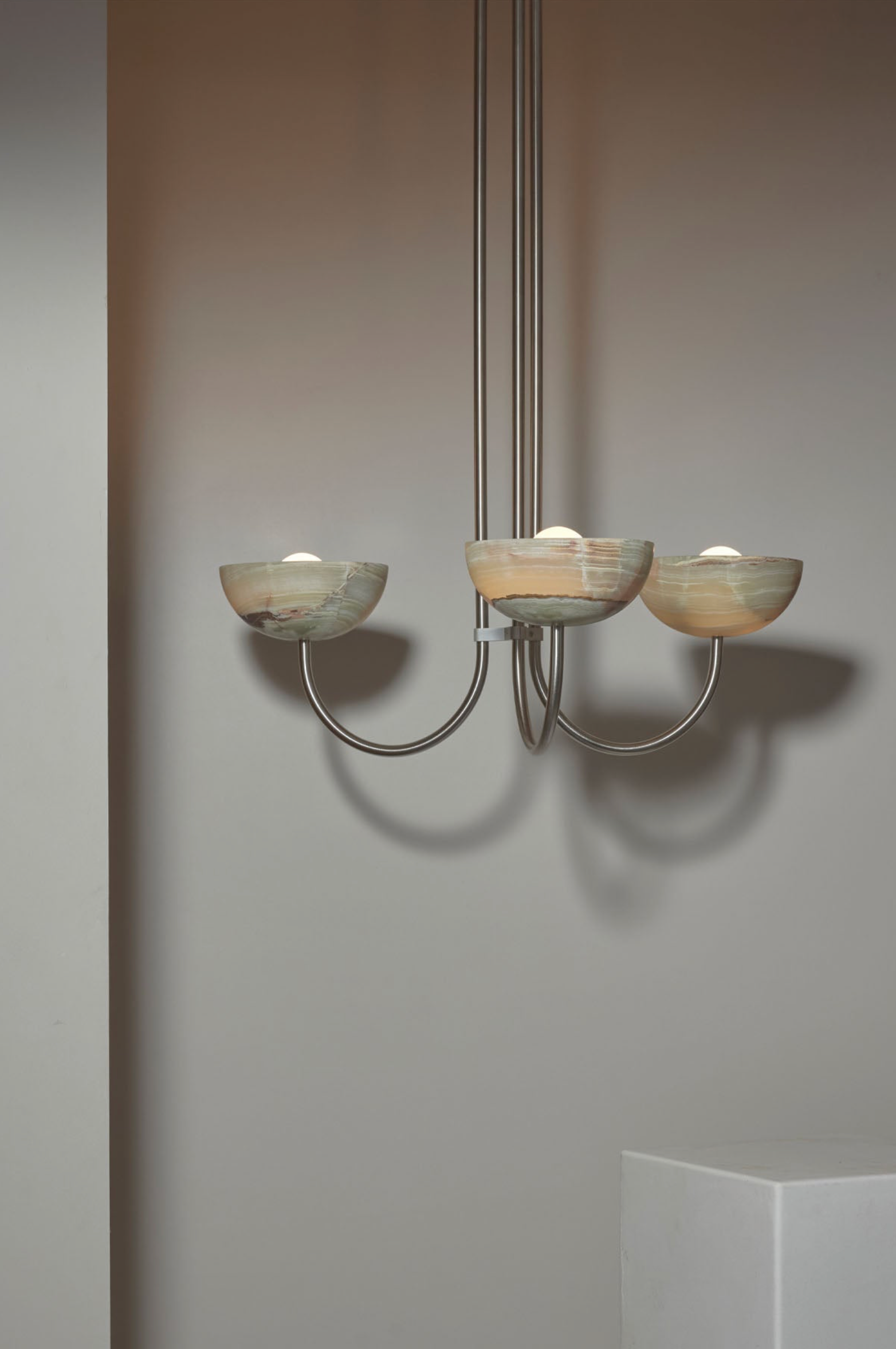 Chandelier with three glass shades against a plain wall