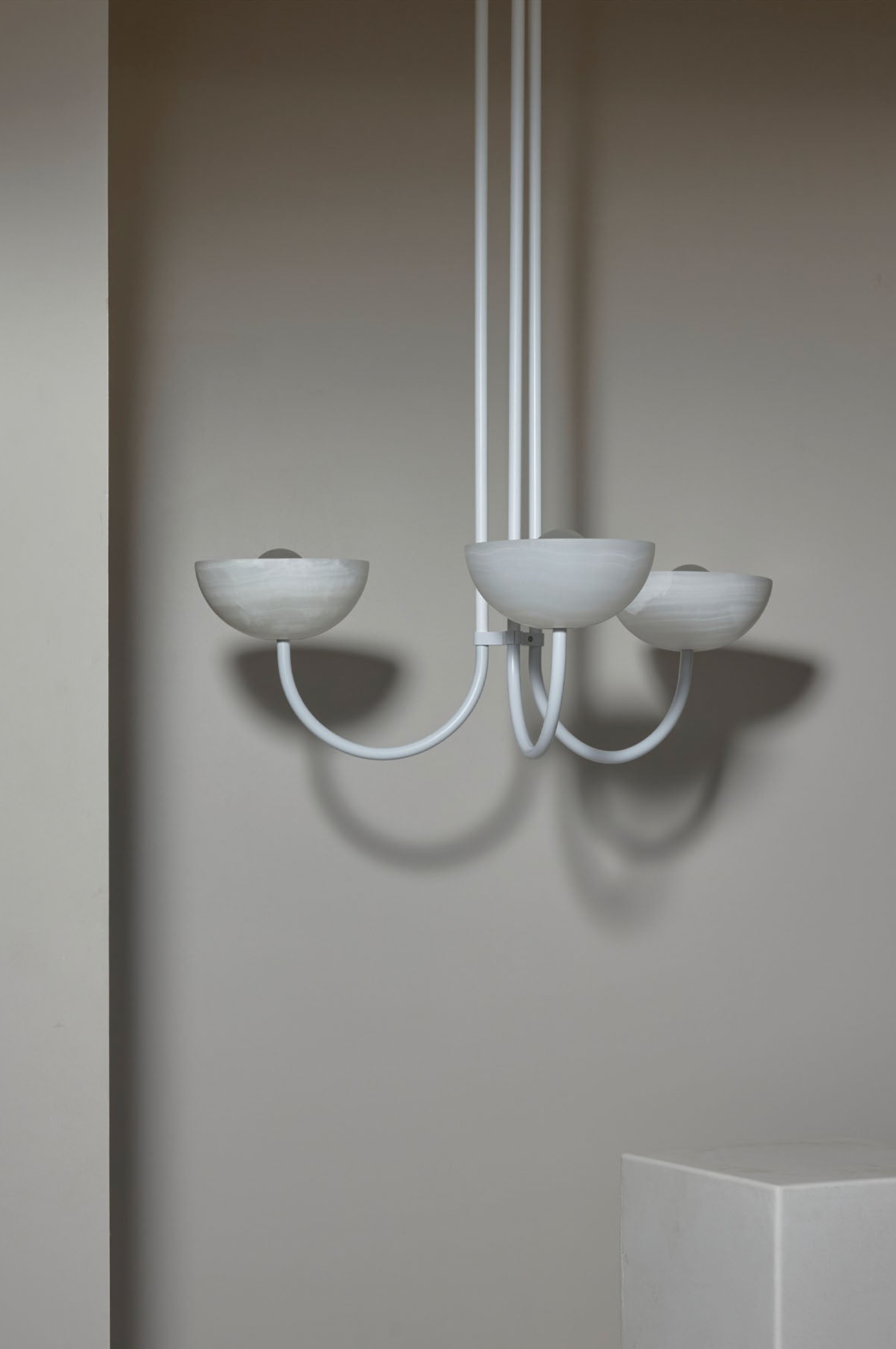 Modern chandelier with three bowl shaped shades on a neutral background