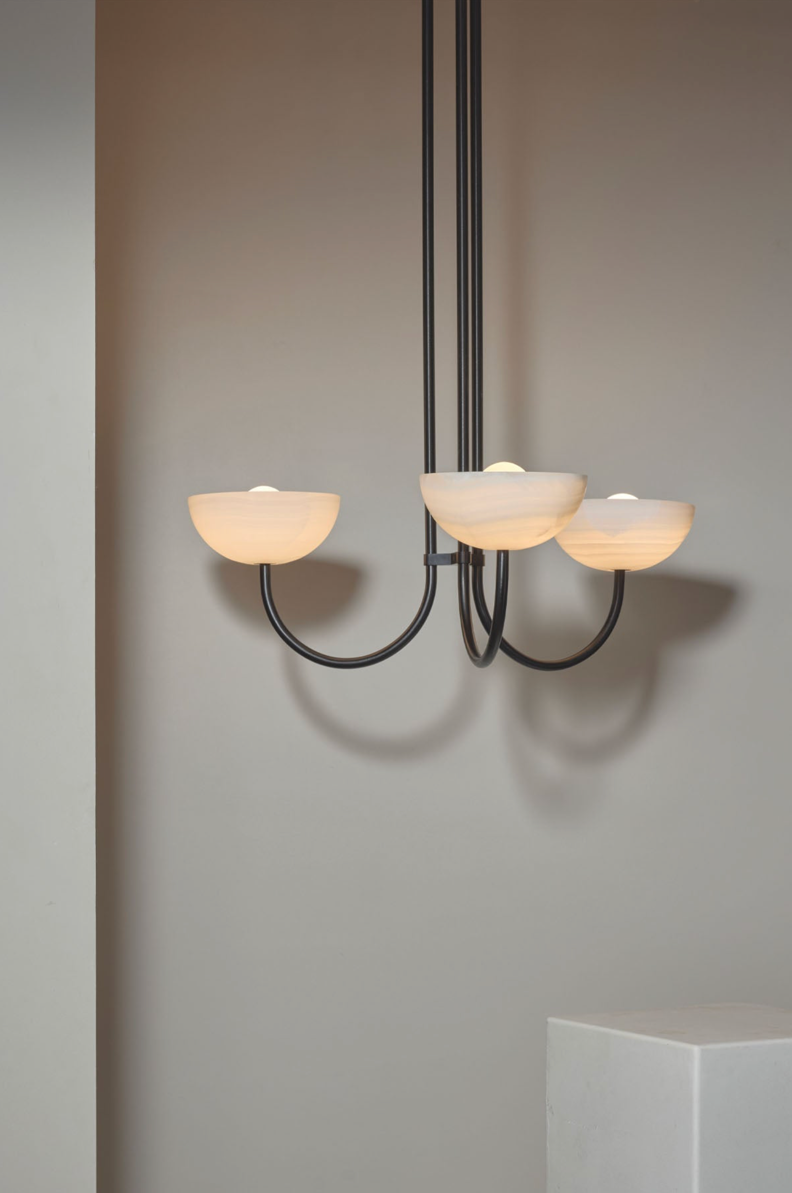 Modern chandelier with three light fixtures on a neutral background