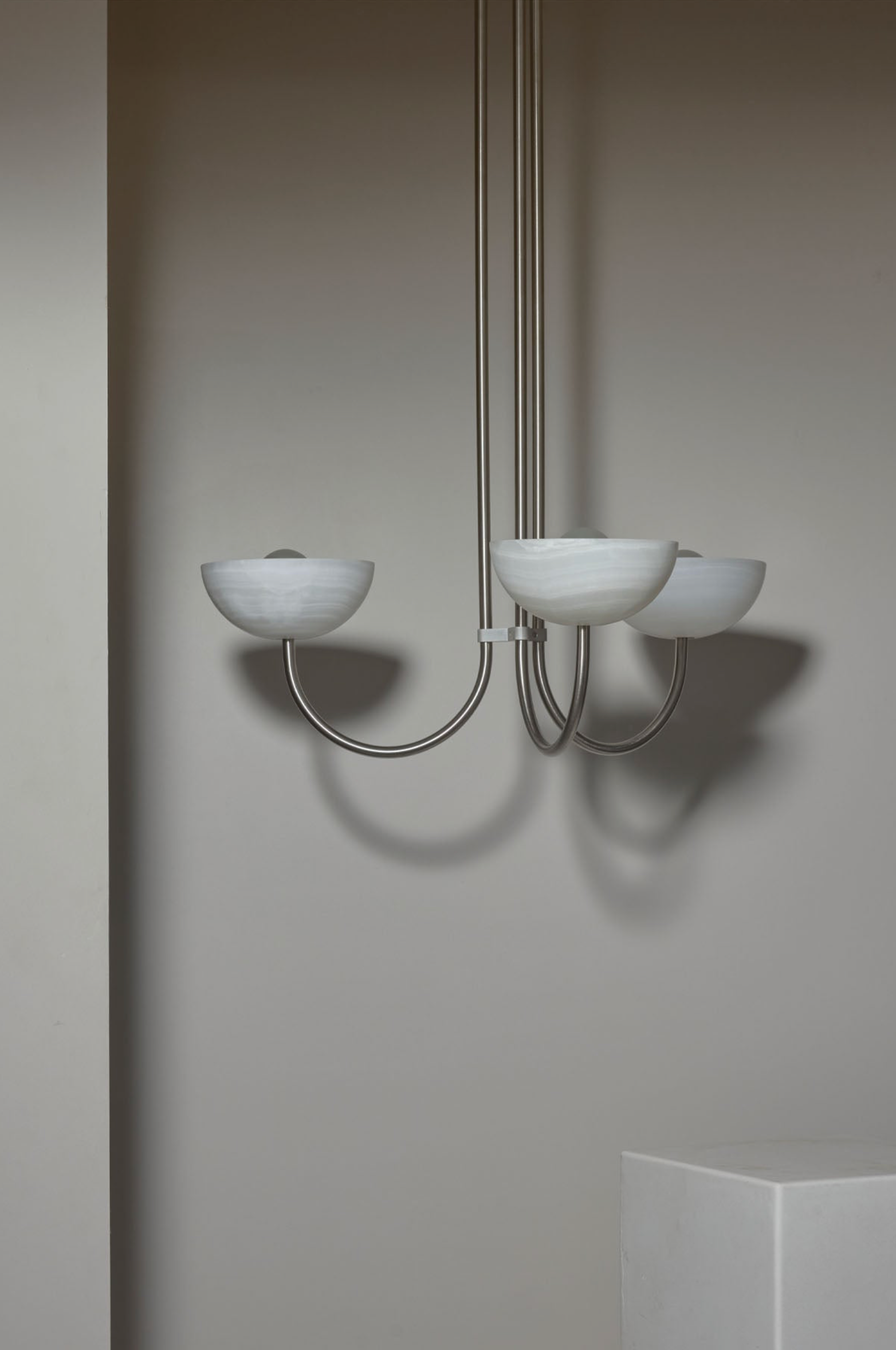Modern chandelier with three glass shades on a neutral background