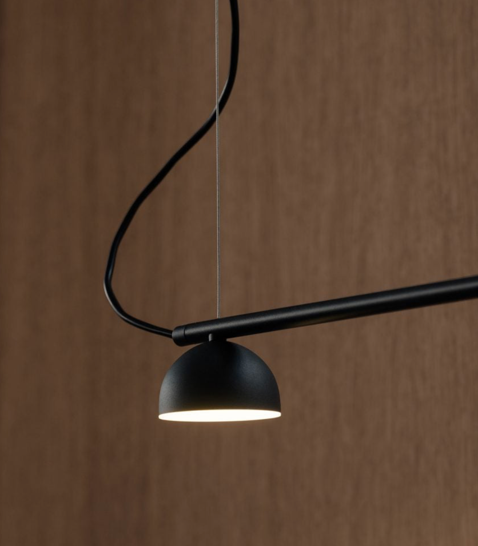 Modern black pendant light against a brown background