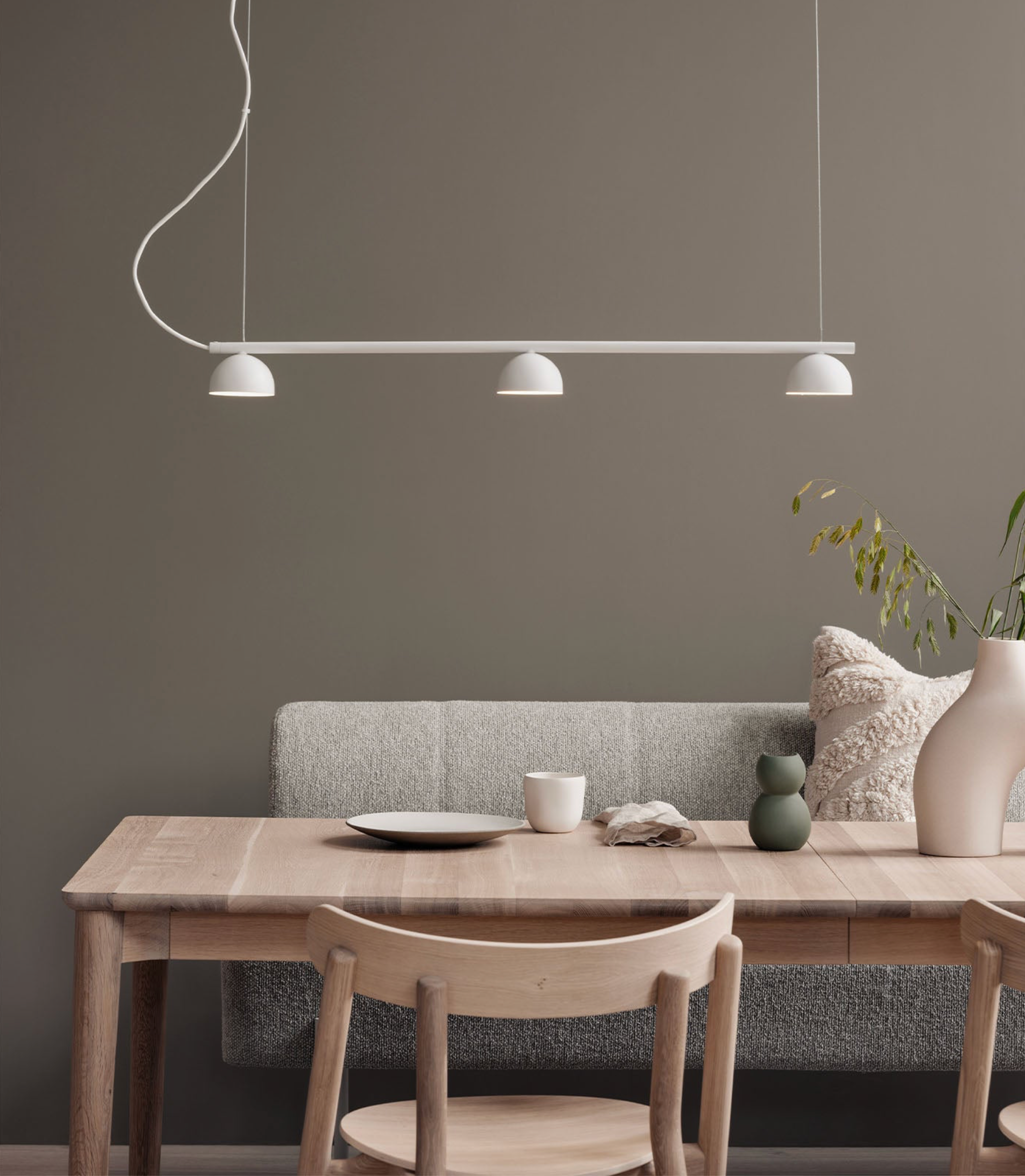 Dining area with wooden table, chairs, and a grey sofa against a dark grey wall.
