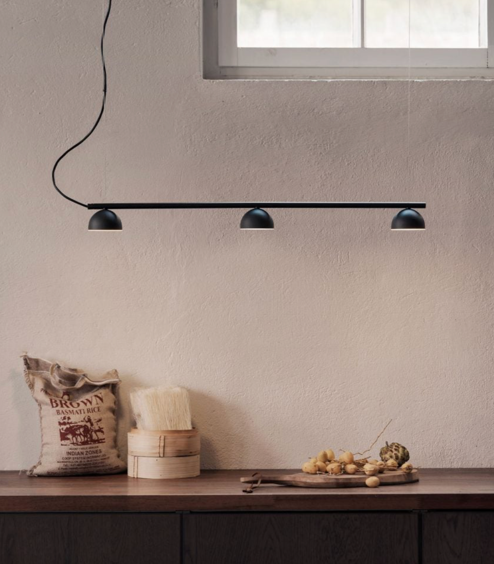 Modern black pendant light fixture on a neutral wall with decorative items below.