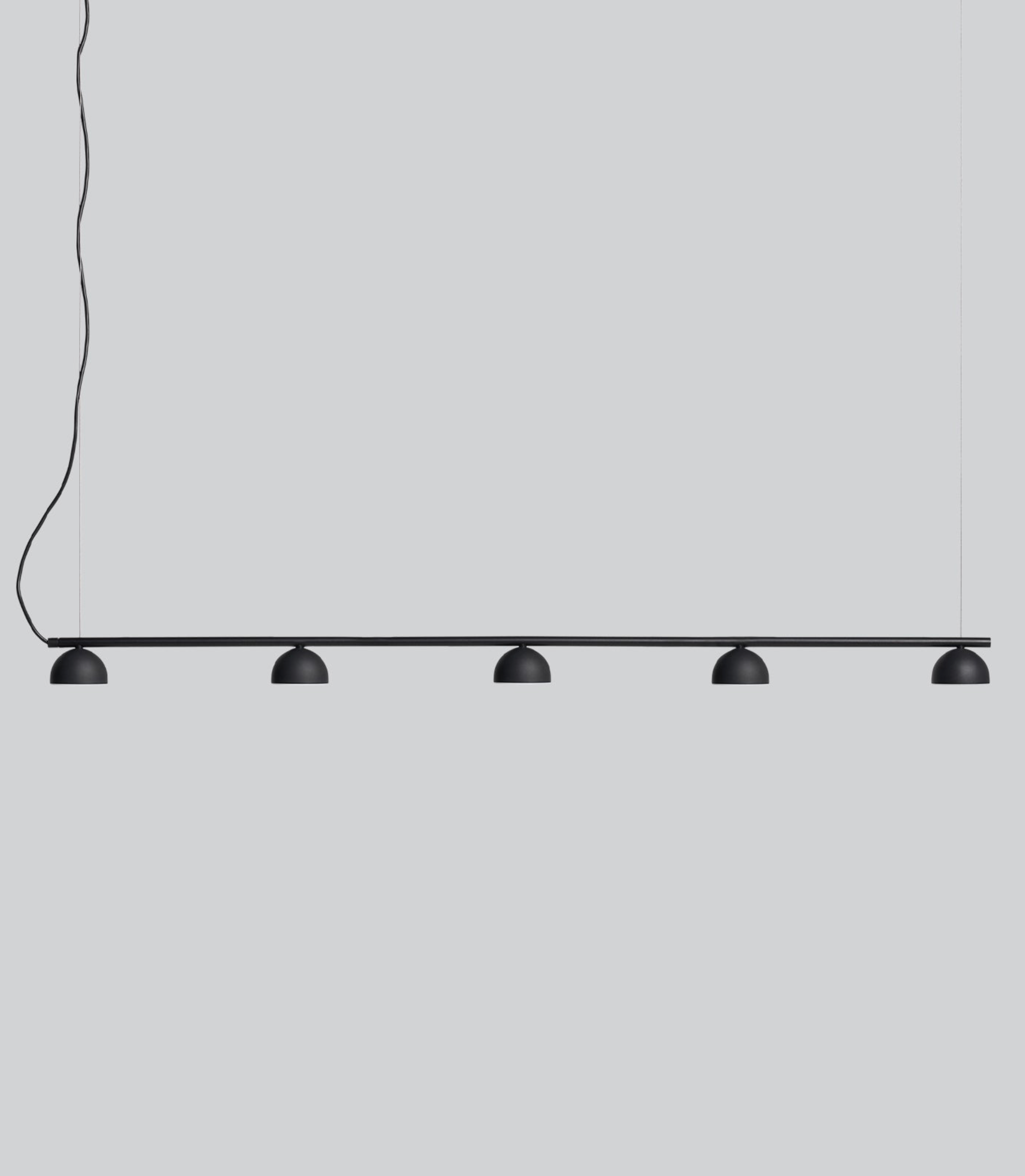 Modern pendant light with five black lampshades on a grey background