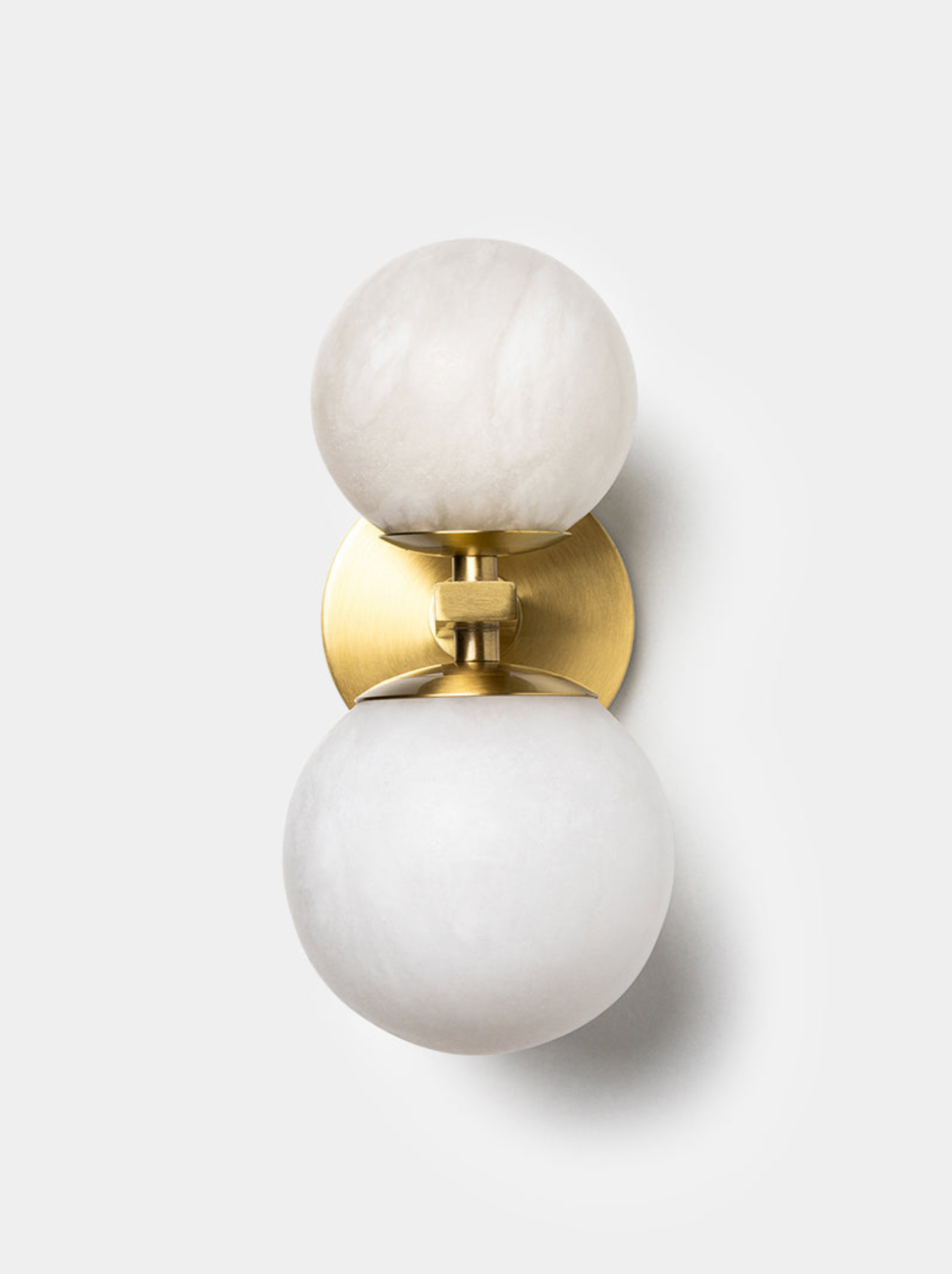 Wall sconce with white spherical shades and gold accents on a light background