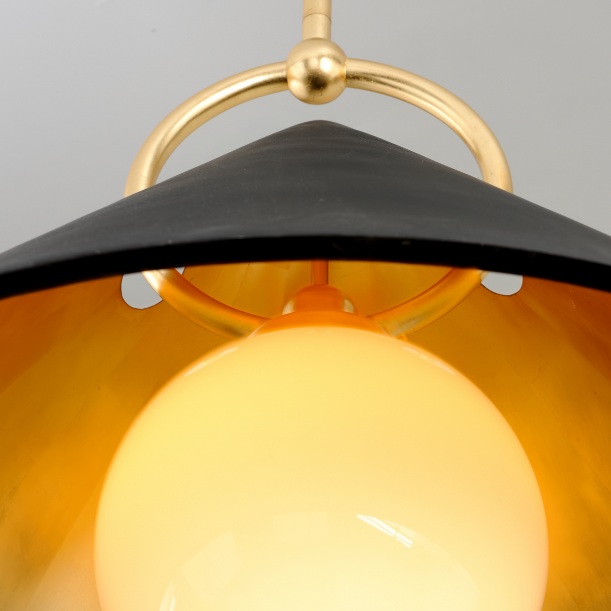 Close-up of a pendant light with black shade and gold fixture.