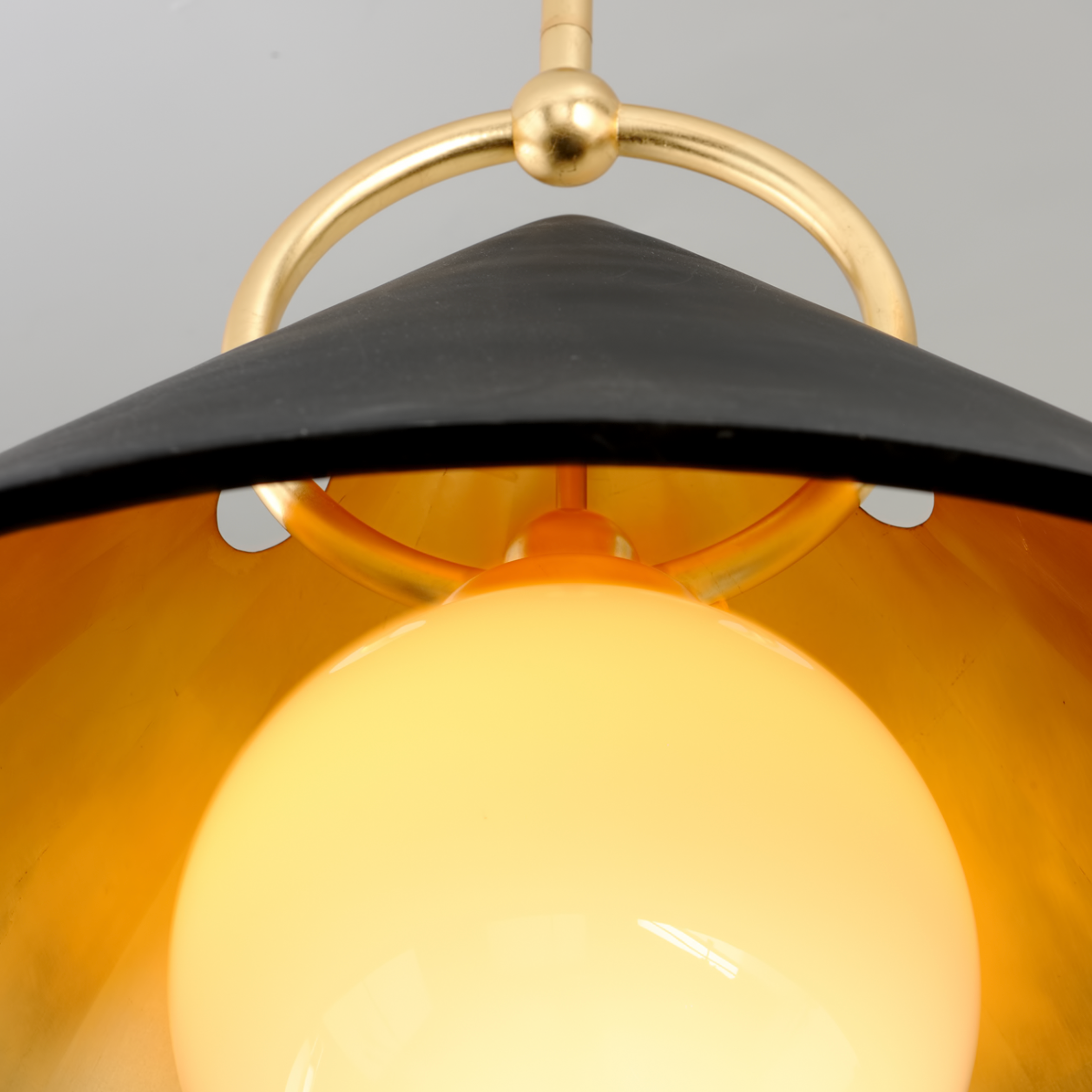 Close-up of a pendant light with black shade and gold fixture.