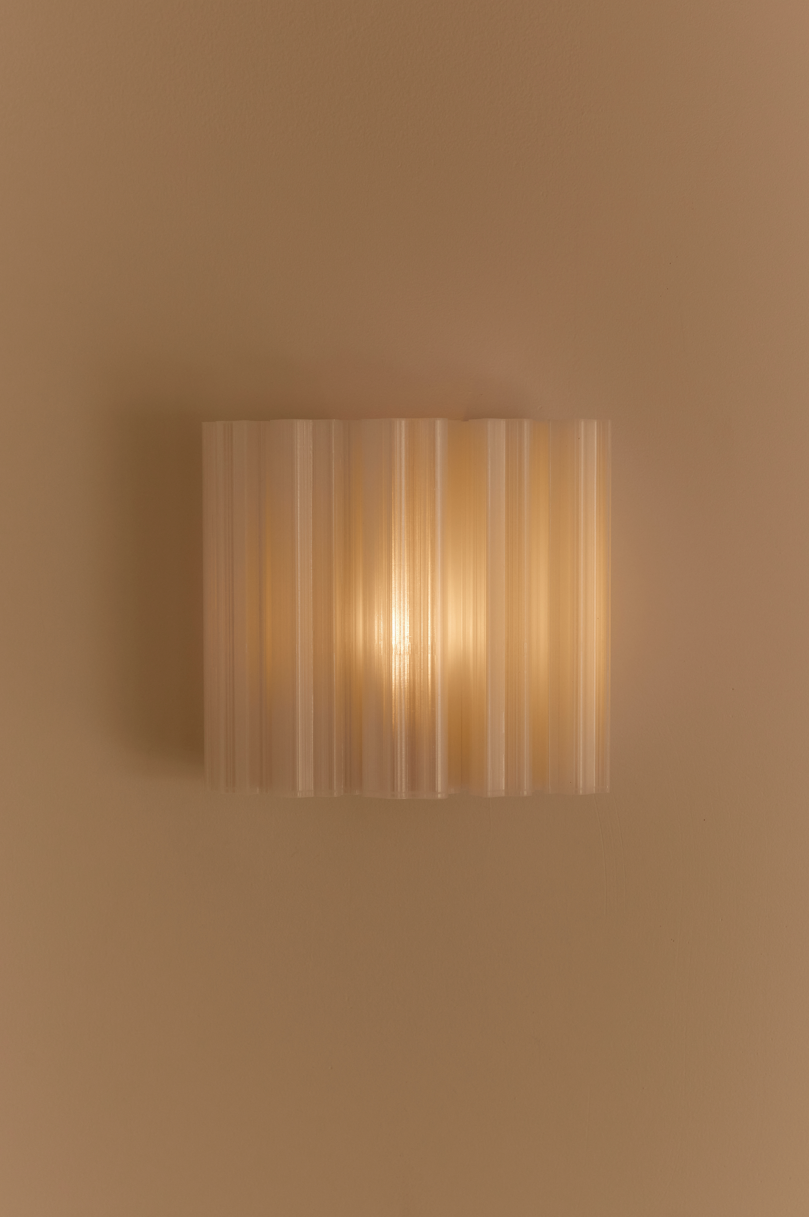 Wall-mounted 3D printed light fixture with striped design on a beige wall