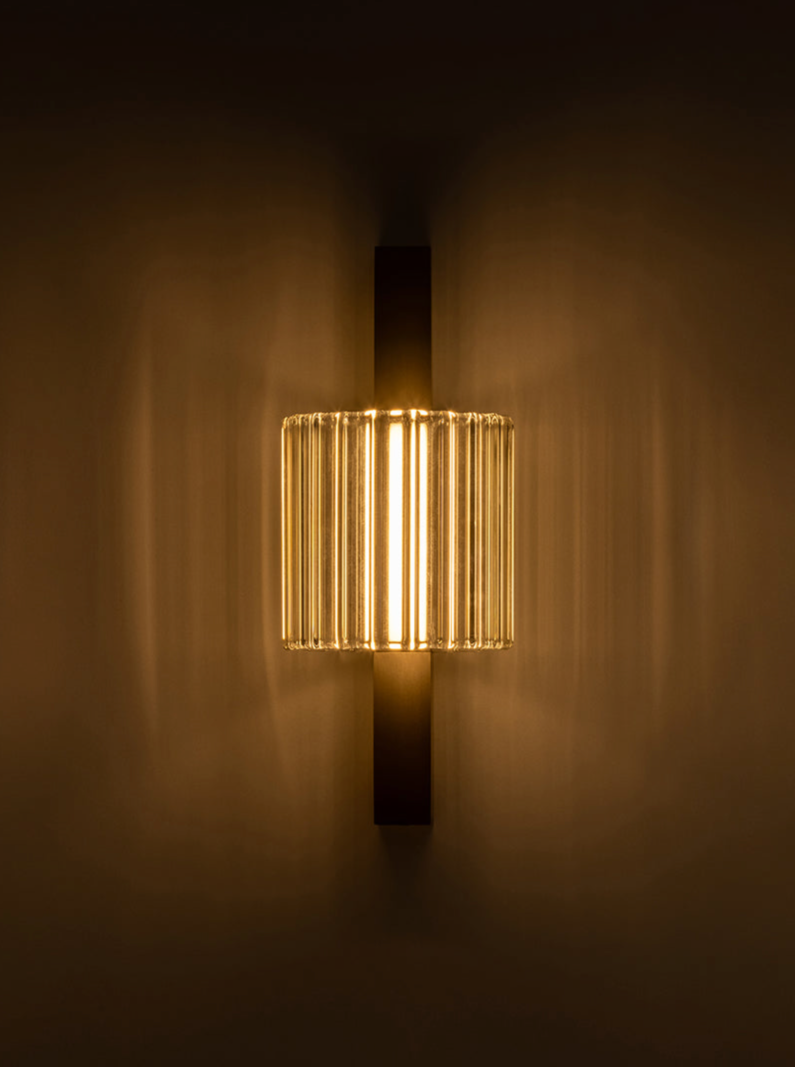 Wall-mounted light fixture with ribbed design on a dark background