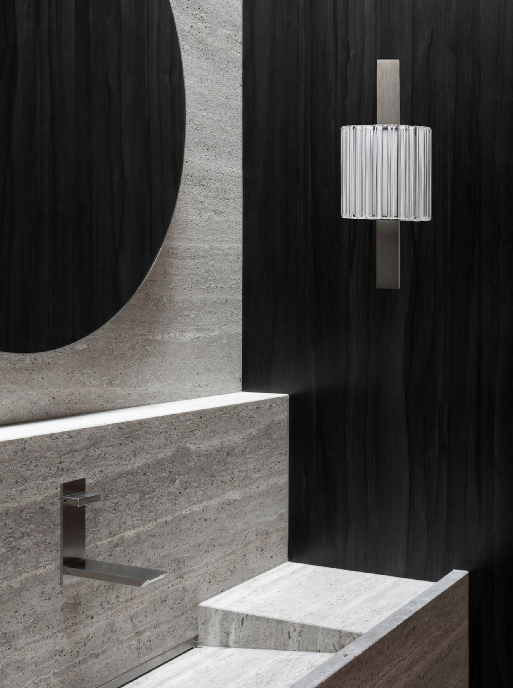 Modern bathroom interior with concrete walls and a wall light fixture.