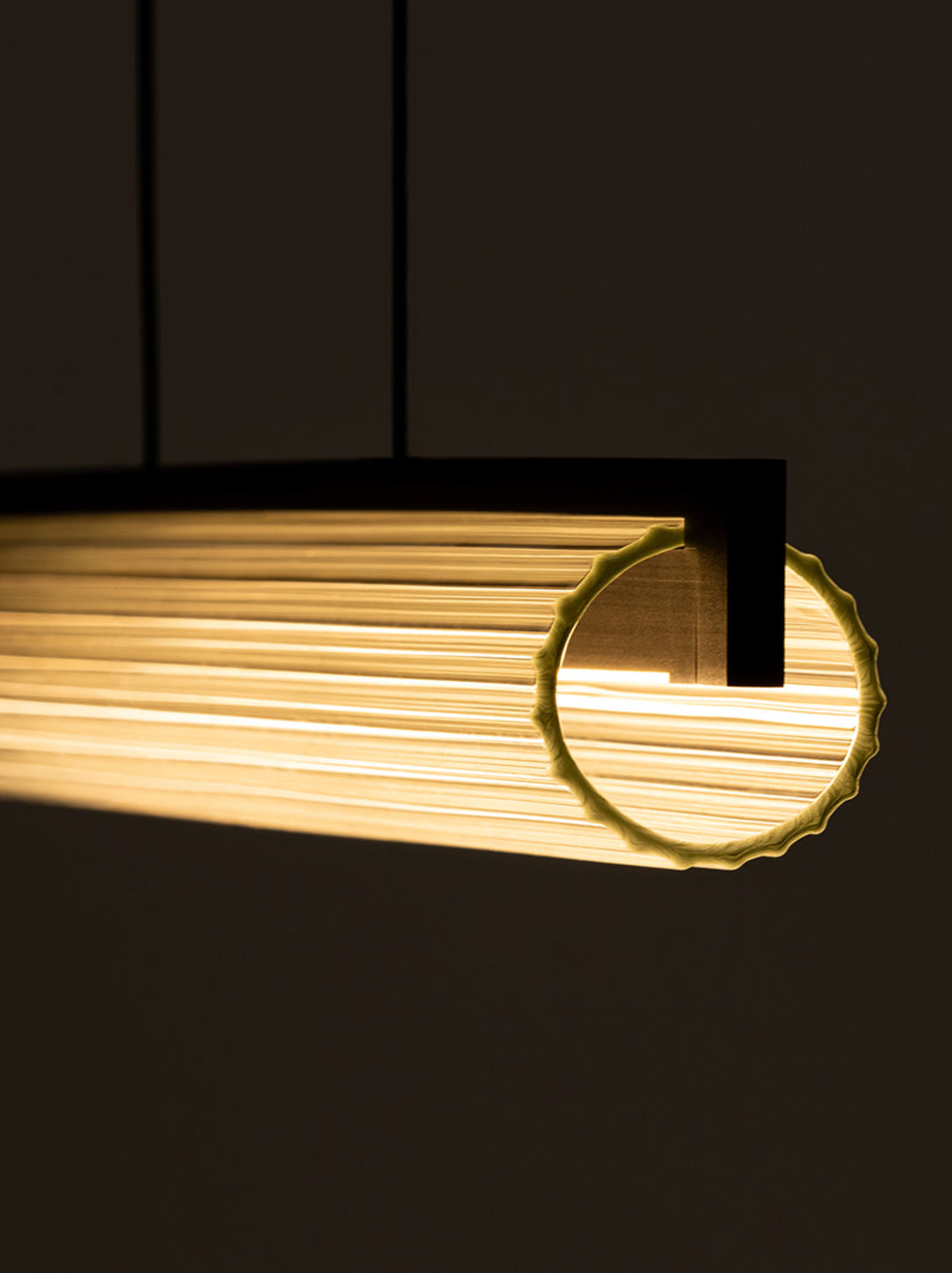 Gold cylindrical linear light with a circular cutout on a black background