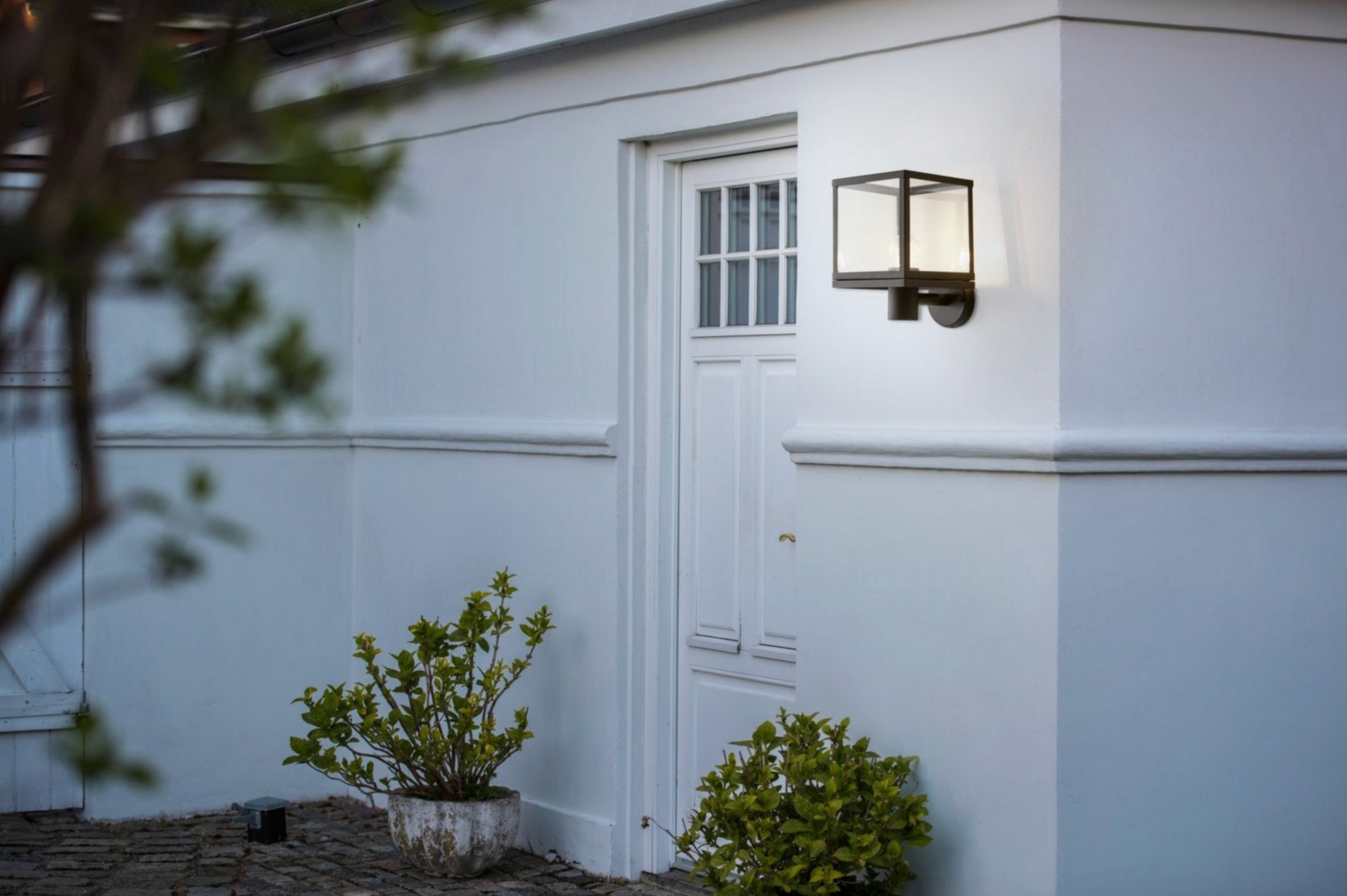 White building exterior with a door and outdoor wall light fixture.