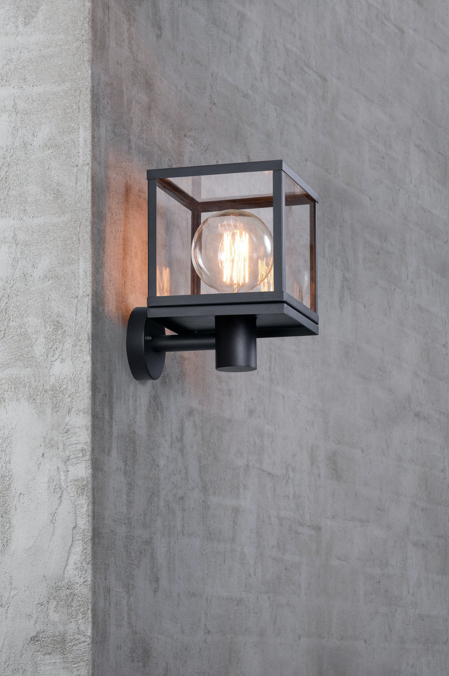 Black outdoor wall light fixture on a gray concrete wall