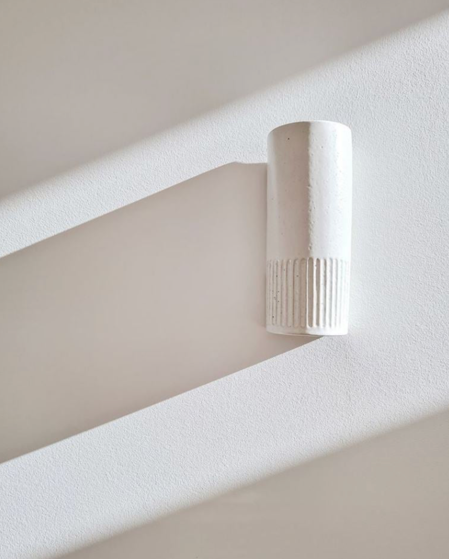 White cylindrical interior wall light fixture on a white wall