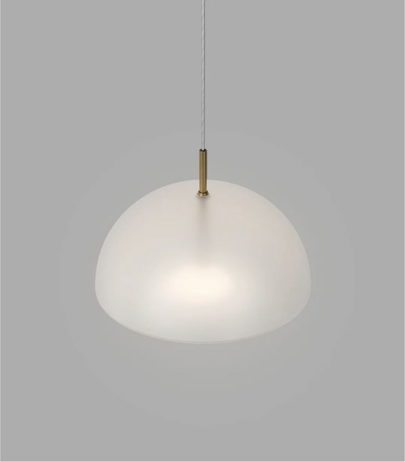 Dome glass pendant light with a brass fixture on a grey background