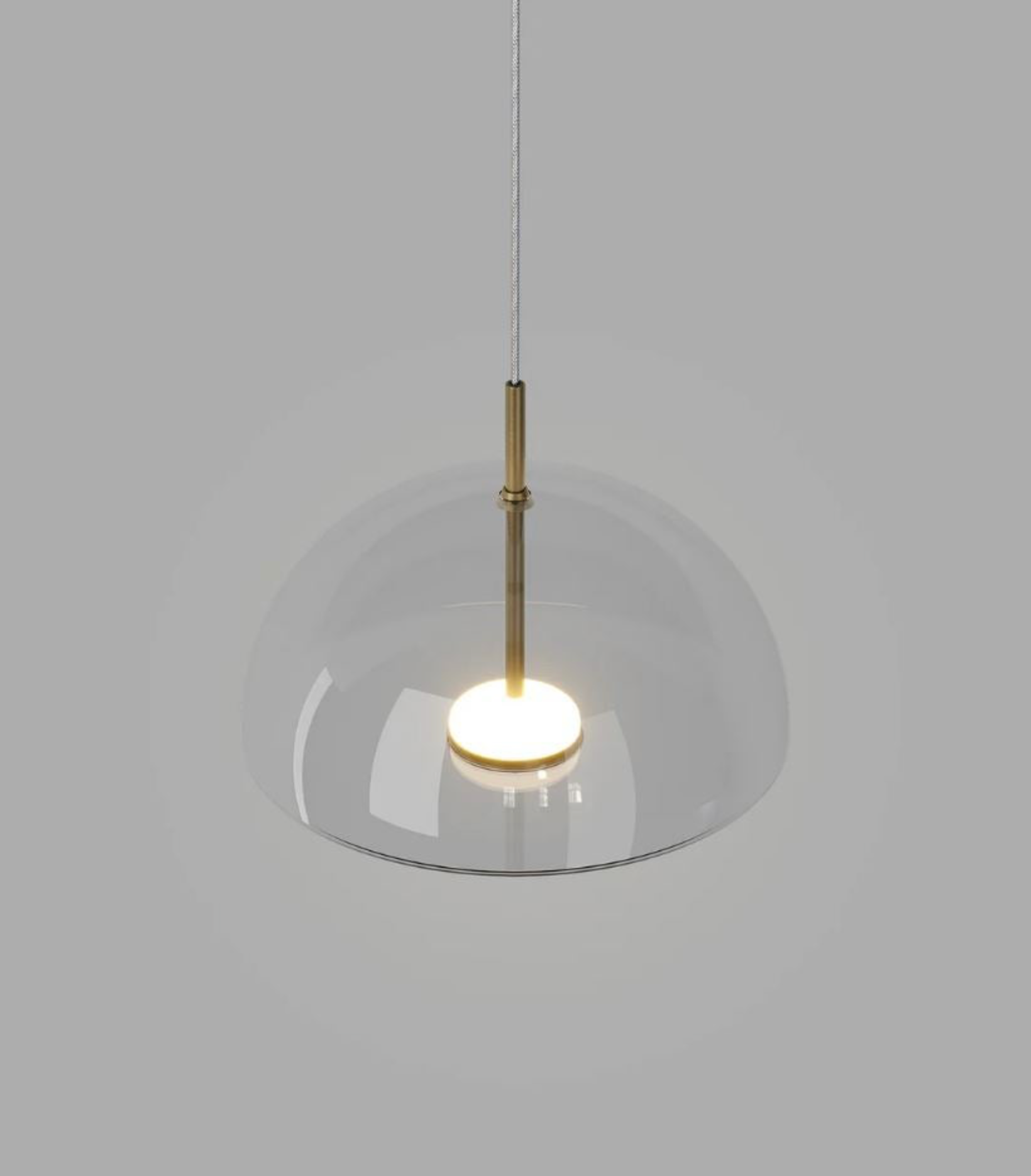 Modern pendant light with glass shade and brass fixture on a plain background