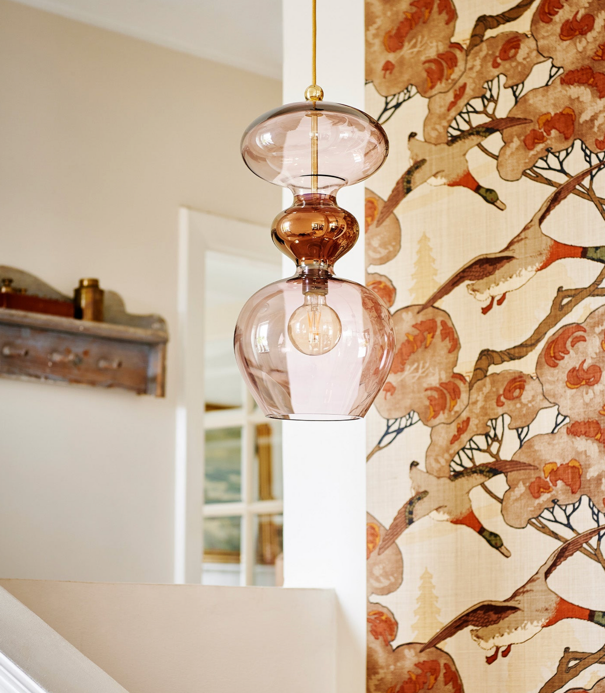 Decorative glass pendant light with floral wallpaper in the background