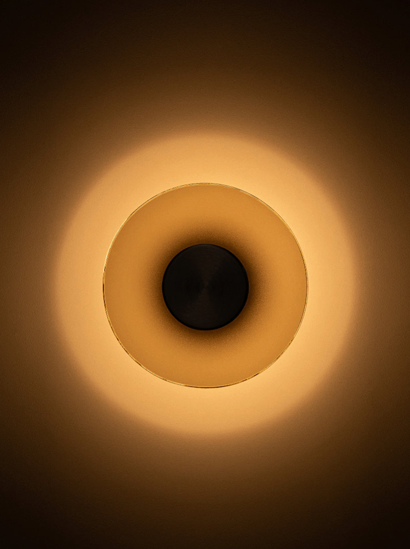 Round wall light fixture with warm glow on a dark background