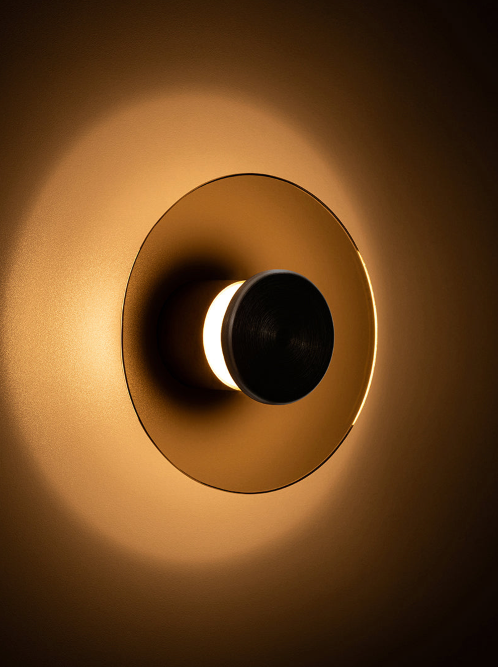 Gold circular wall light fixture on a dark background