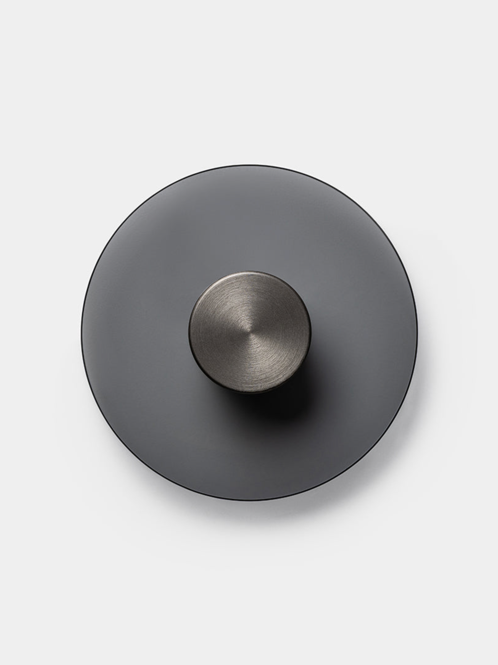 Round metallic wall light with a smaller round component on a light grey background