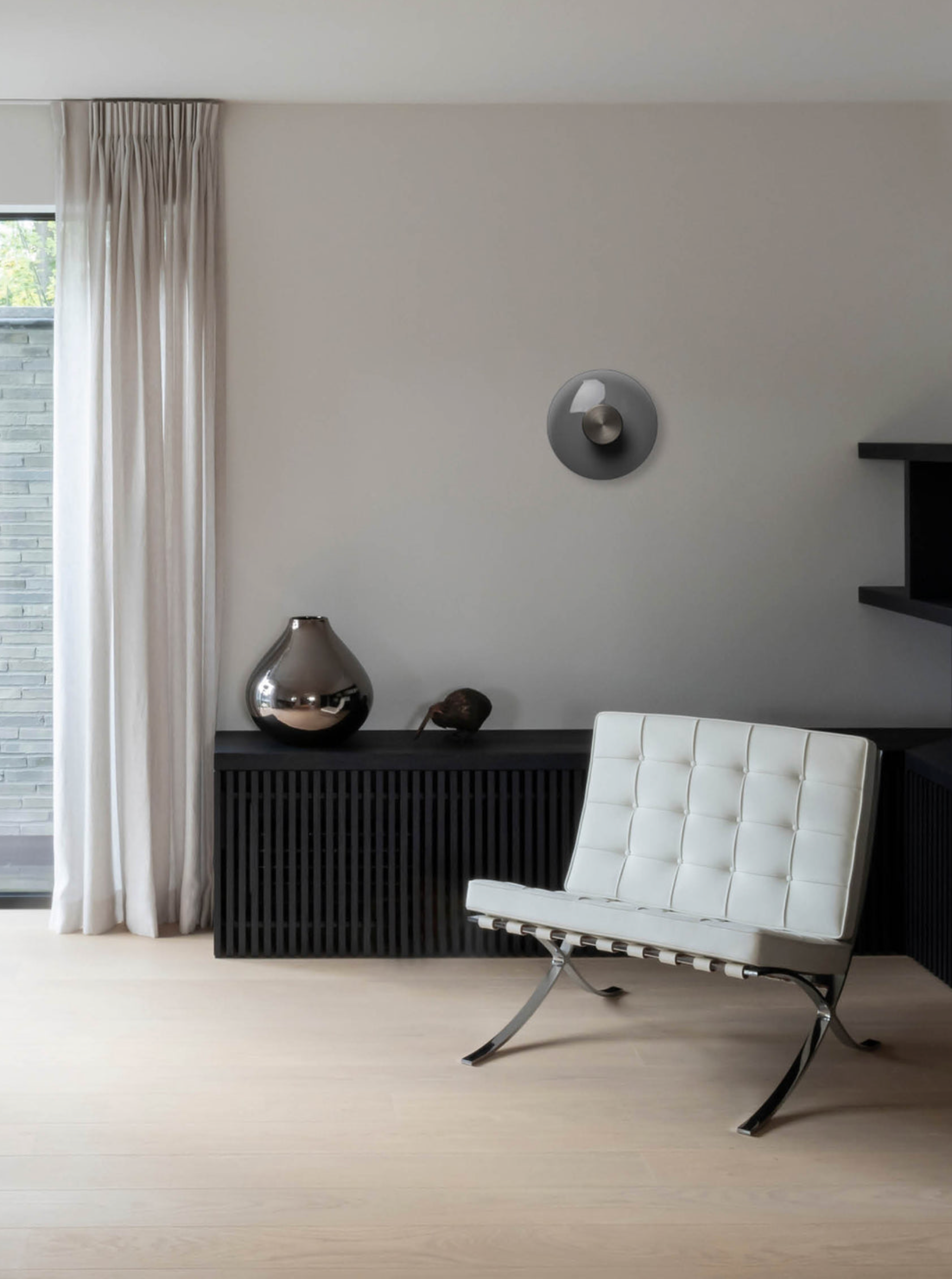 Modern living room with a white chair, black console table, and decorative items.