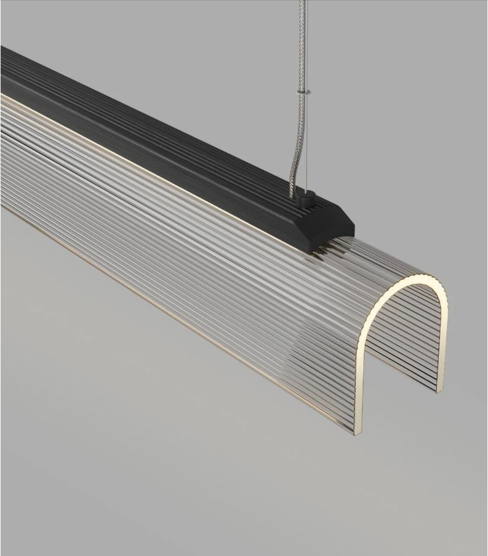 Curved glass linear light fixture on a grey background
