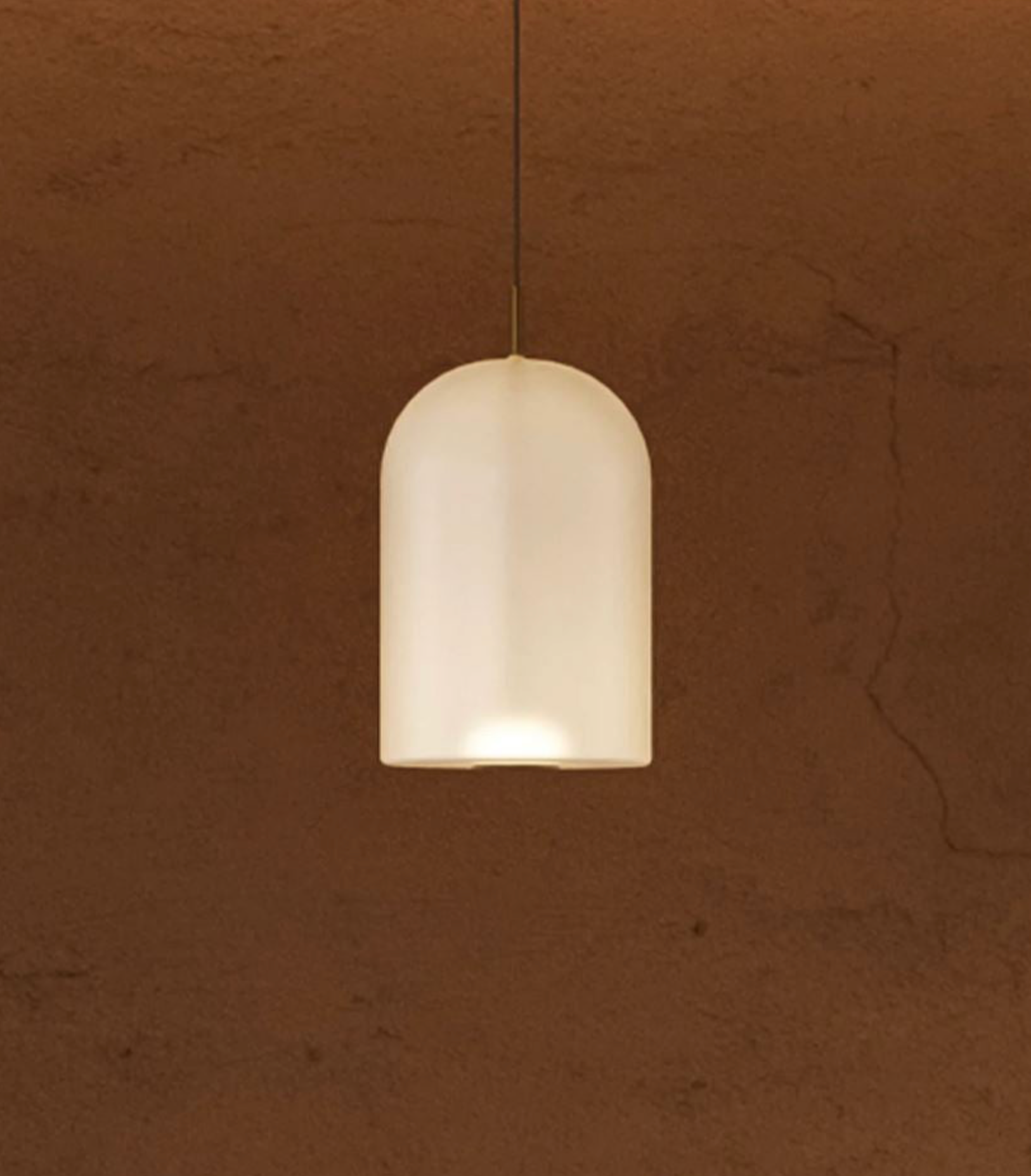Frosted glass pendant light against a brown textured wall