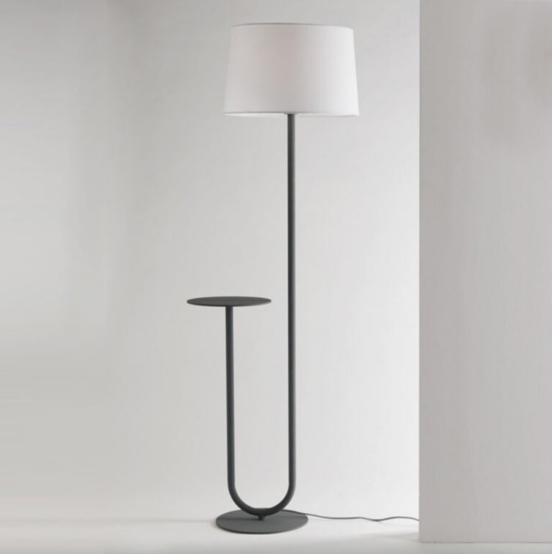 Modern floor lamp with a white shade and black base on a plain background