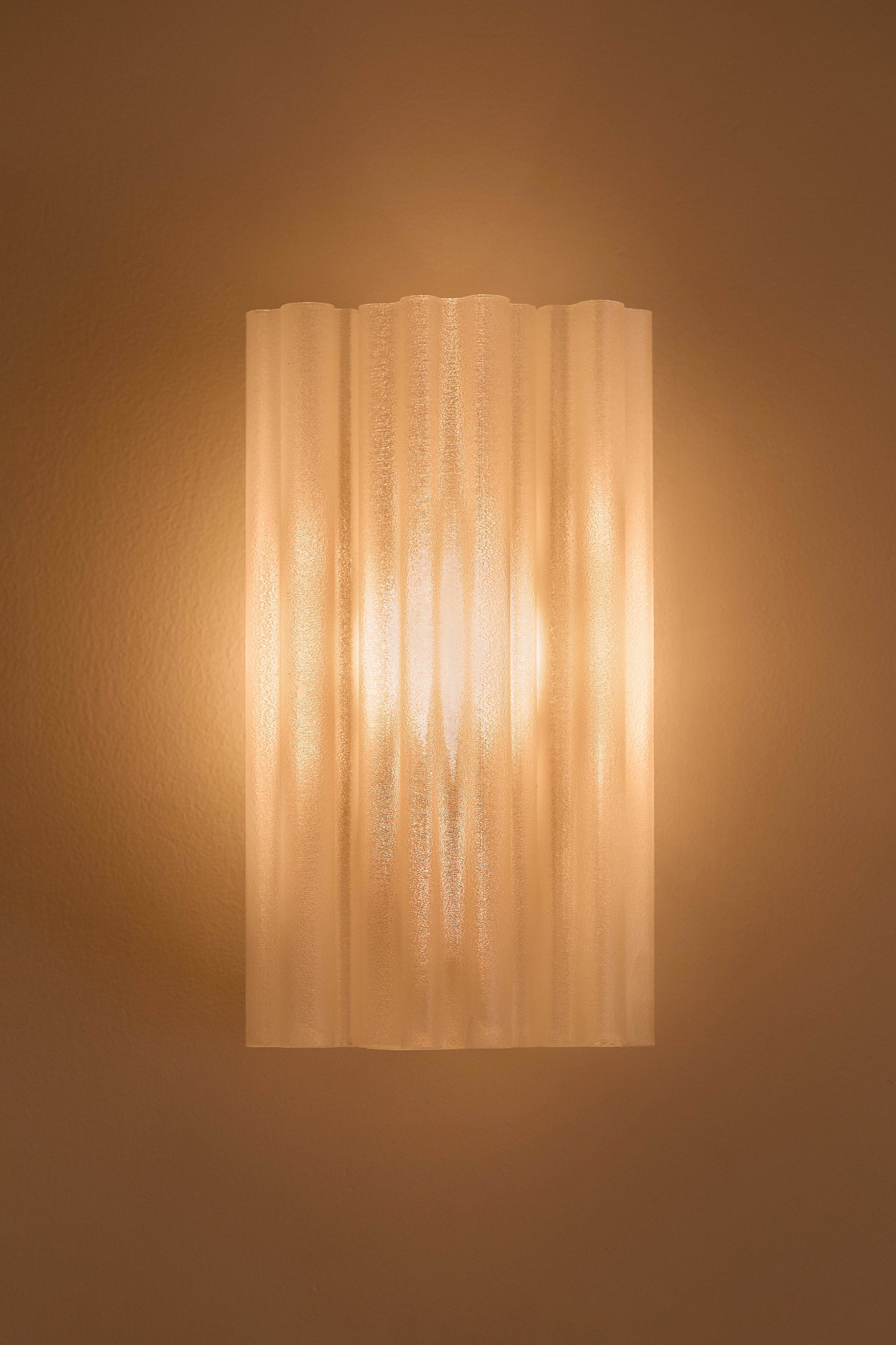 Wall-mounted 3D printed light fixture with a textured shade on a beige wall.