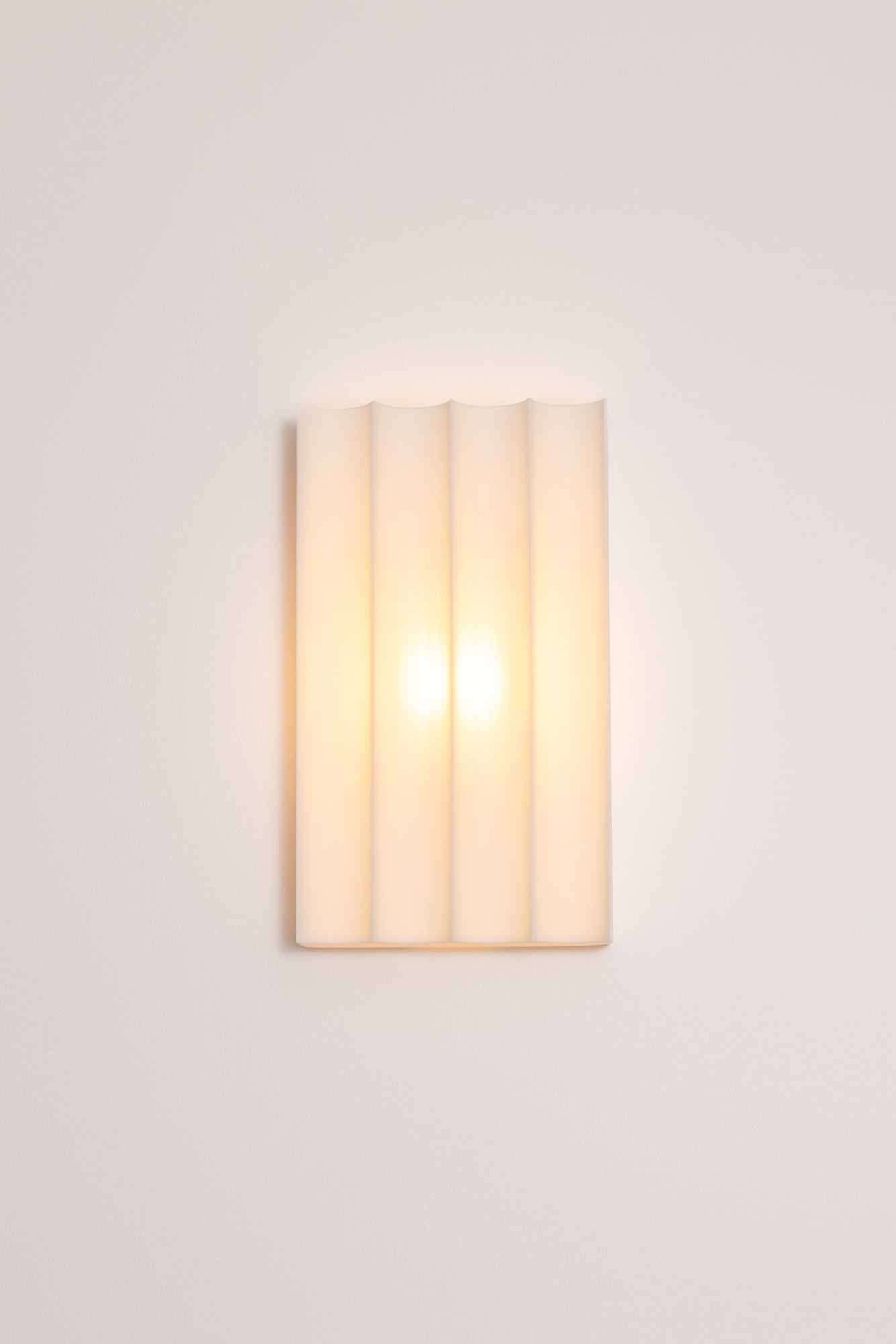 Wall-mounted 3D printed wall light fixture with a cylindrical design on a plain background