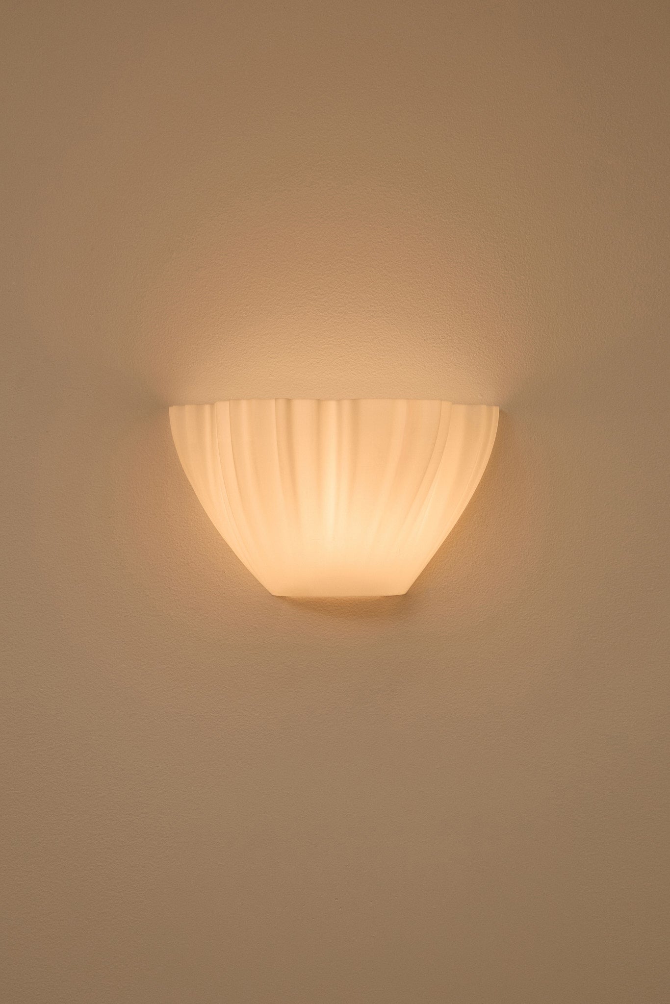 Wall-mounted 3D printed wall light fixture casting a warm glow on a beige wall