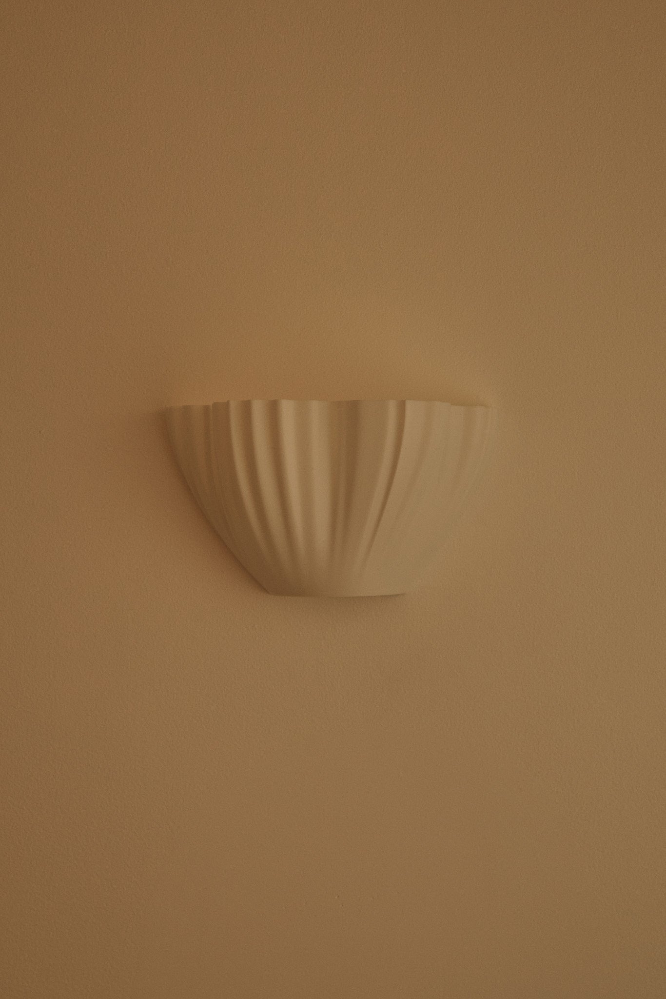 Decorative wall-mounted 3D printed wall light on a beige wall