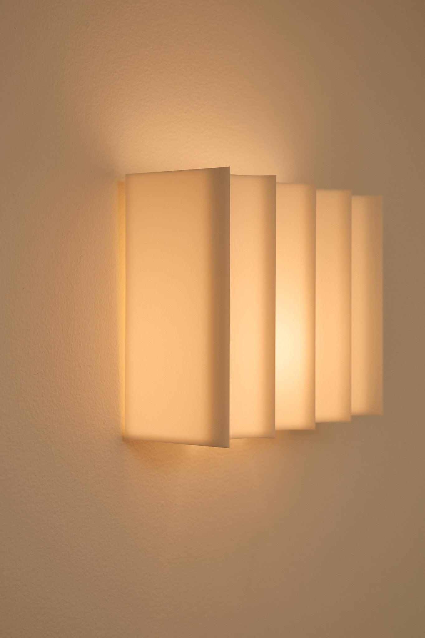 Wall-mounted 3D printed light fixture on a beige wall.