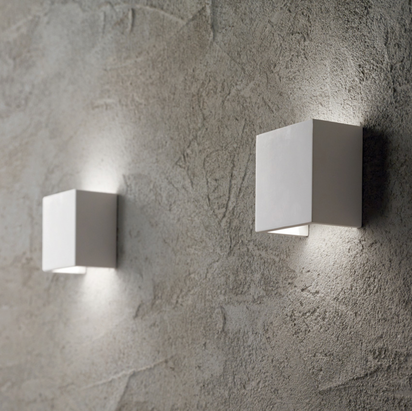 Two square wall lights on a textured gray wall